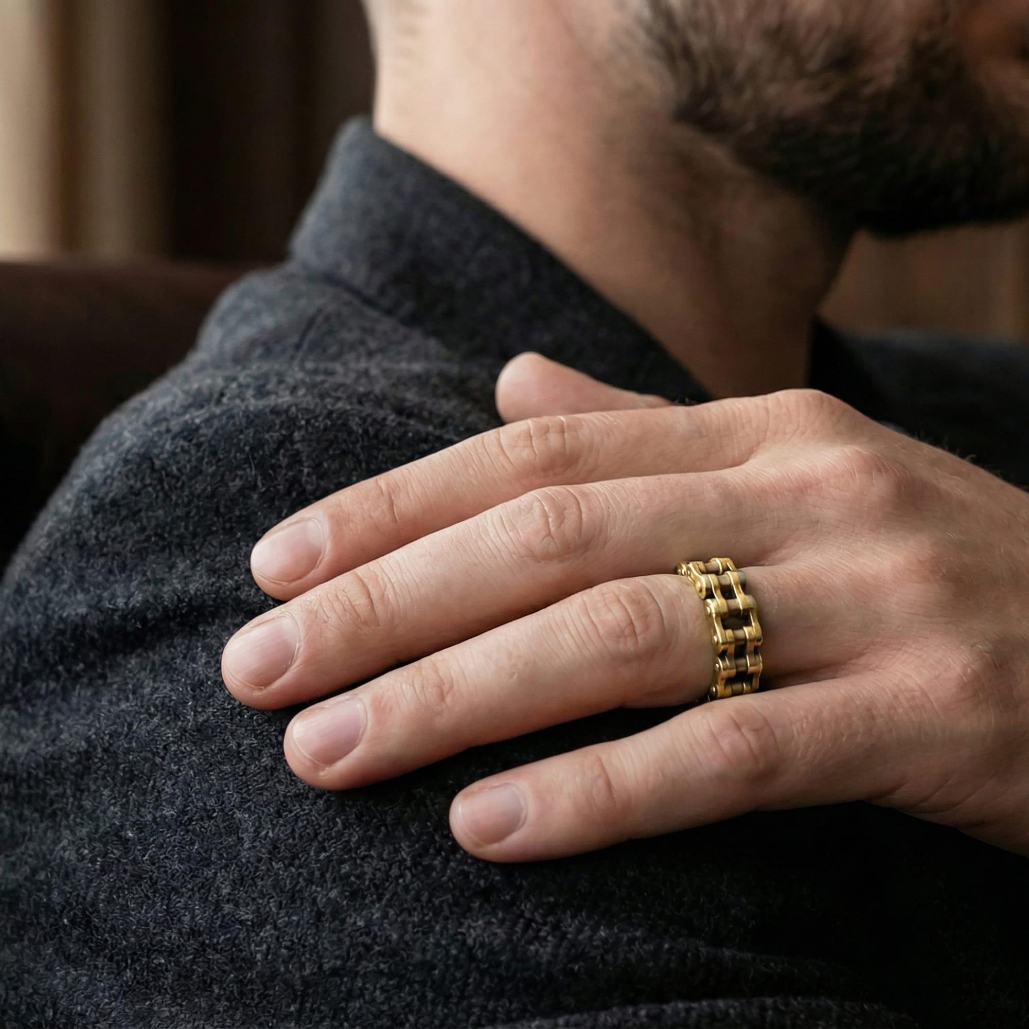 Gold plated industrial chain ring worn by man as a rugged statement band with retrofuturistic streetwear appeal