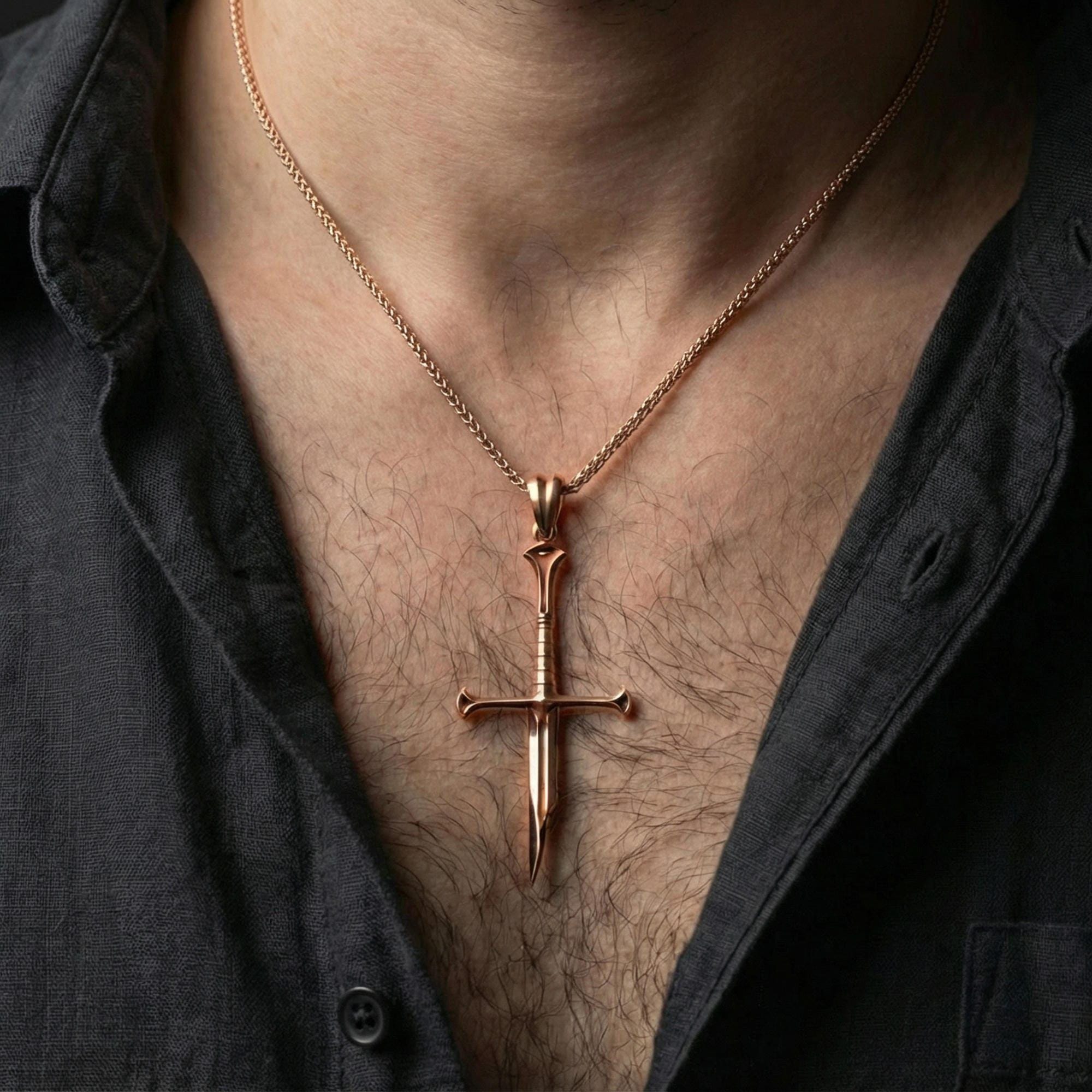 Rose gold plated sword pendant necklace worn on neck, lifestyle composition with dark clothing, crisp blade silhouette