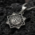 Load image into Gallery viewer, Oxidized Throat Chakra (Vishuddha) pendant on textured volcanic rock, macro close-up, geometric chakra symbol detail, premium studio lighting
