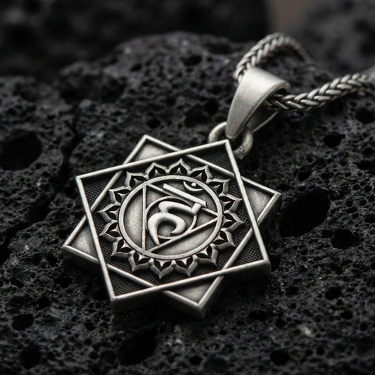 Oxidized Throat Chakra (Vishuddha) pendant on textured volcanic rock, macro close-up, geometric chakra symbol detail, premium studio lighting