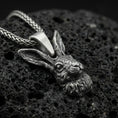 Load image into Gallery viewer, Oxidized rabbit head pendant on textured volcanic rock, macro close-up, detailed fur and ears, dark premium studio lighting
