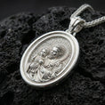 Load image into Gallery viewer, Polished silver Saint Joseph necklace pendant on black volcanic stone background, crisp relief of Saint Joseph and child, high-end product shot
