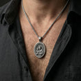 Load image into Gallery viewer, Oxidized Saint Joseph rotating pendant necklace worn on neck, lifestyle close-up on dark outfit, oval medallion centered
