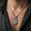 Load image into Gallery viewer, Oxidized Virgin Mary and Baby Jesus pendant necklace worn on neck, lifestyle close-up on dark outfit, rectangular medallion centered
