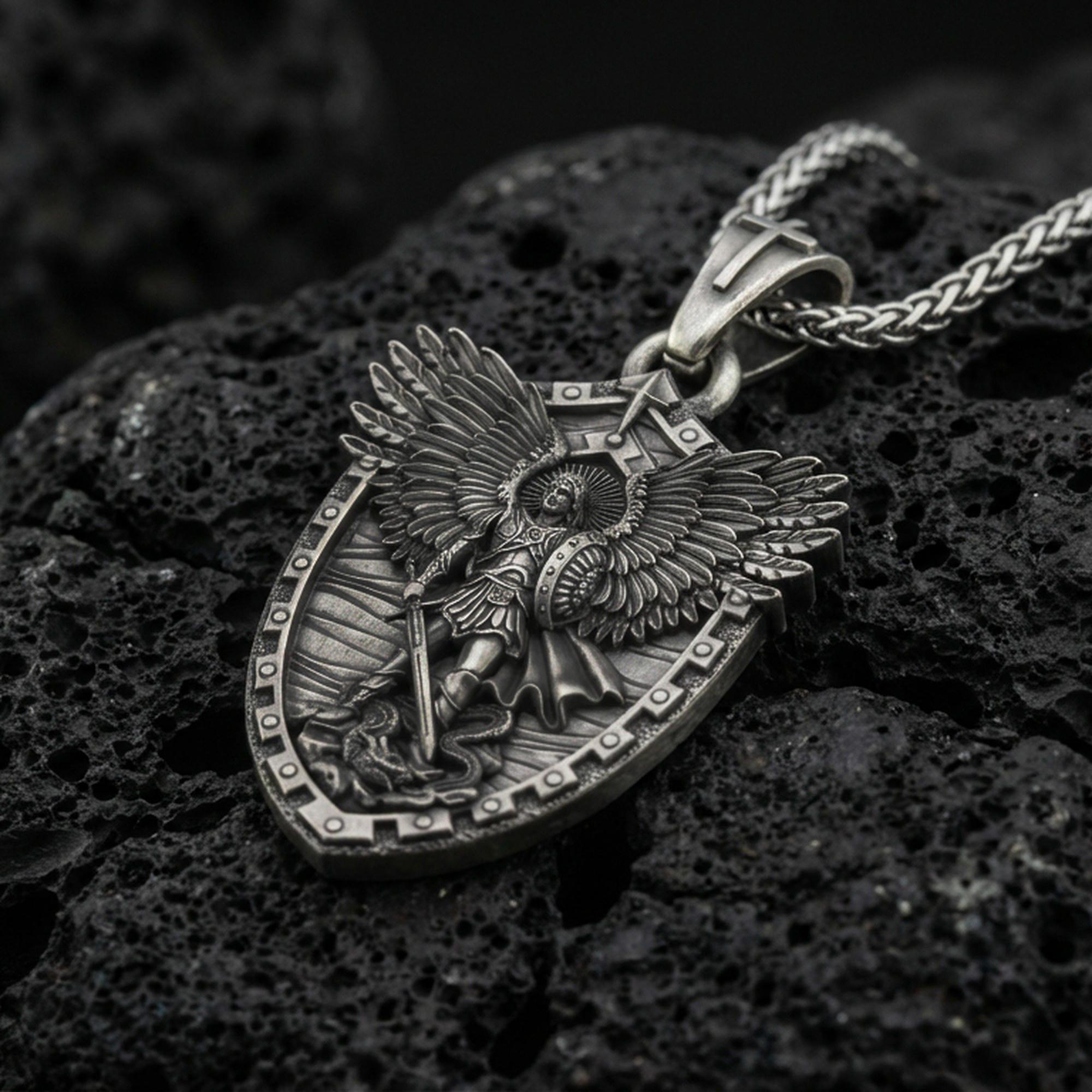 Oxidized Archangel Michael shield pendant on textured volcanic rock, macro close-up, detailed wings and sword relief, premium studio lighting