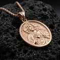 Load image into Gallery viewer, Rose gold plated Sacred Heart Jesus pendant on volcanic rock, premium macro product photo, sharp medal border and sacred heart motif
