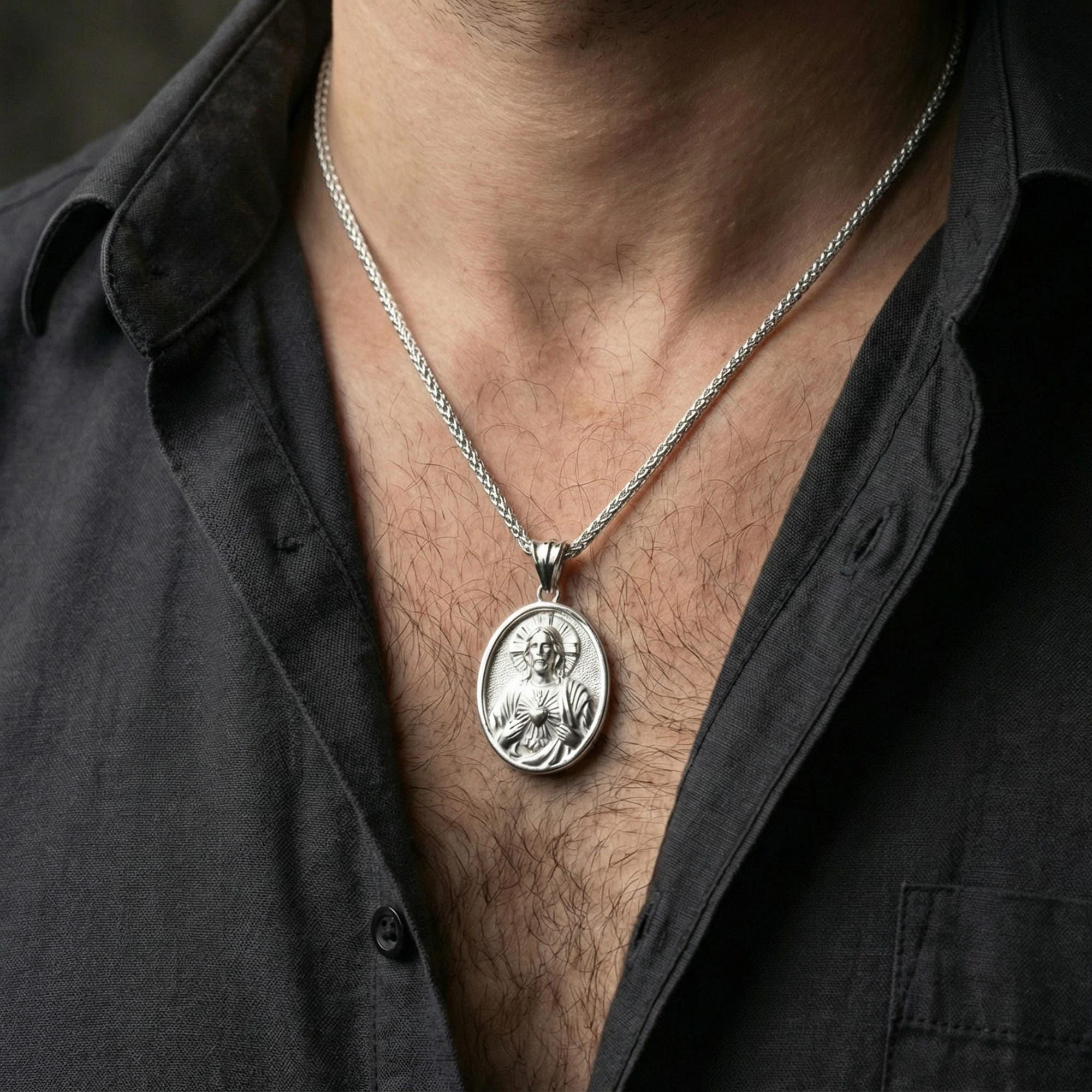 Polished silver Sacred Heart Jesus pendant on chain worn on neck, natural lifestyle framing, halo and heart detail visible