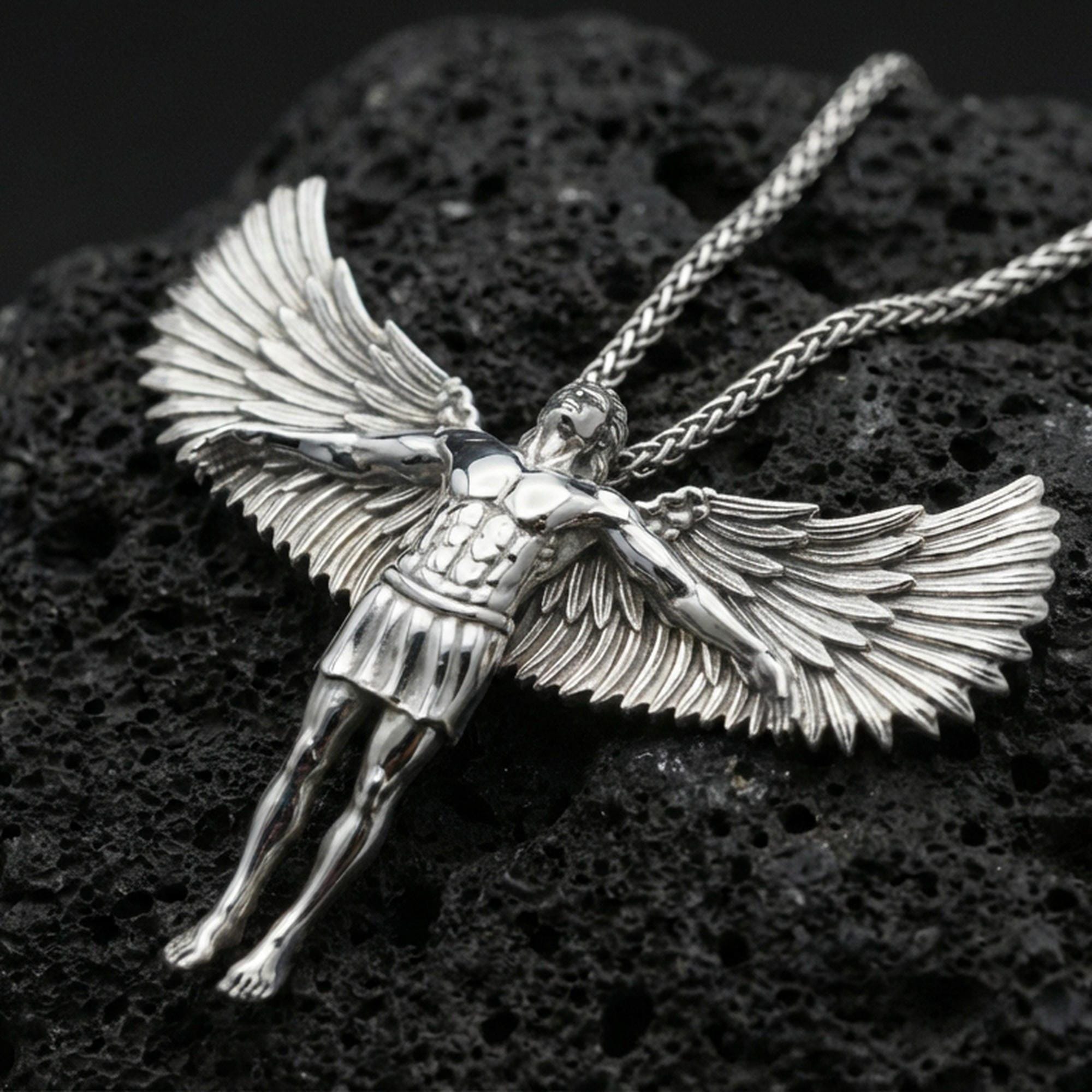 Polished silver Archangel Michael necklace pendant on black volcanic stone background, crisp wing feathers and armor details, high-end product shot