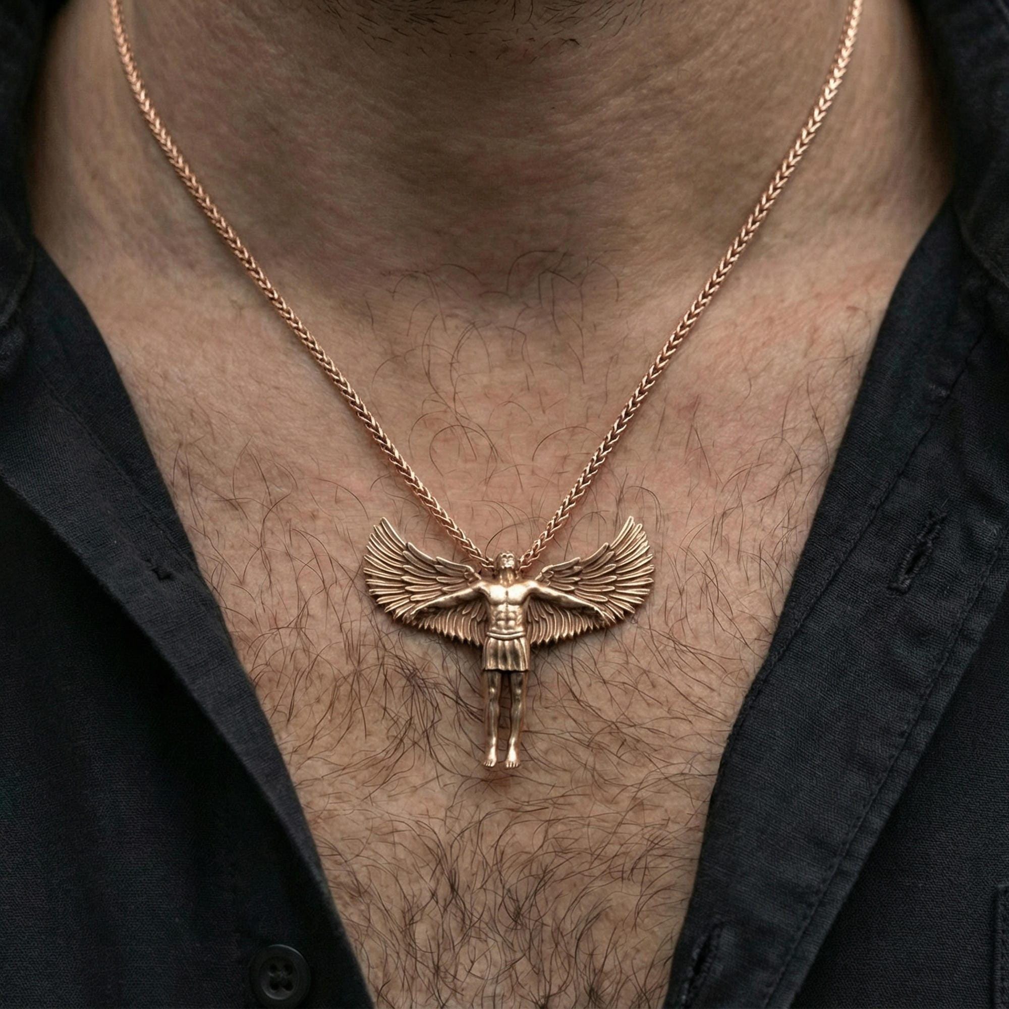 Rose gold plated Archangel Michael pendant necklace worn on neck, lifestyle composition with dark clothing, crisp angel silhouette