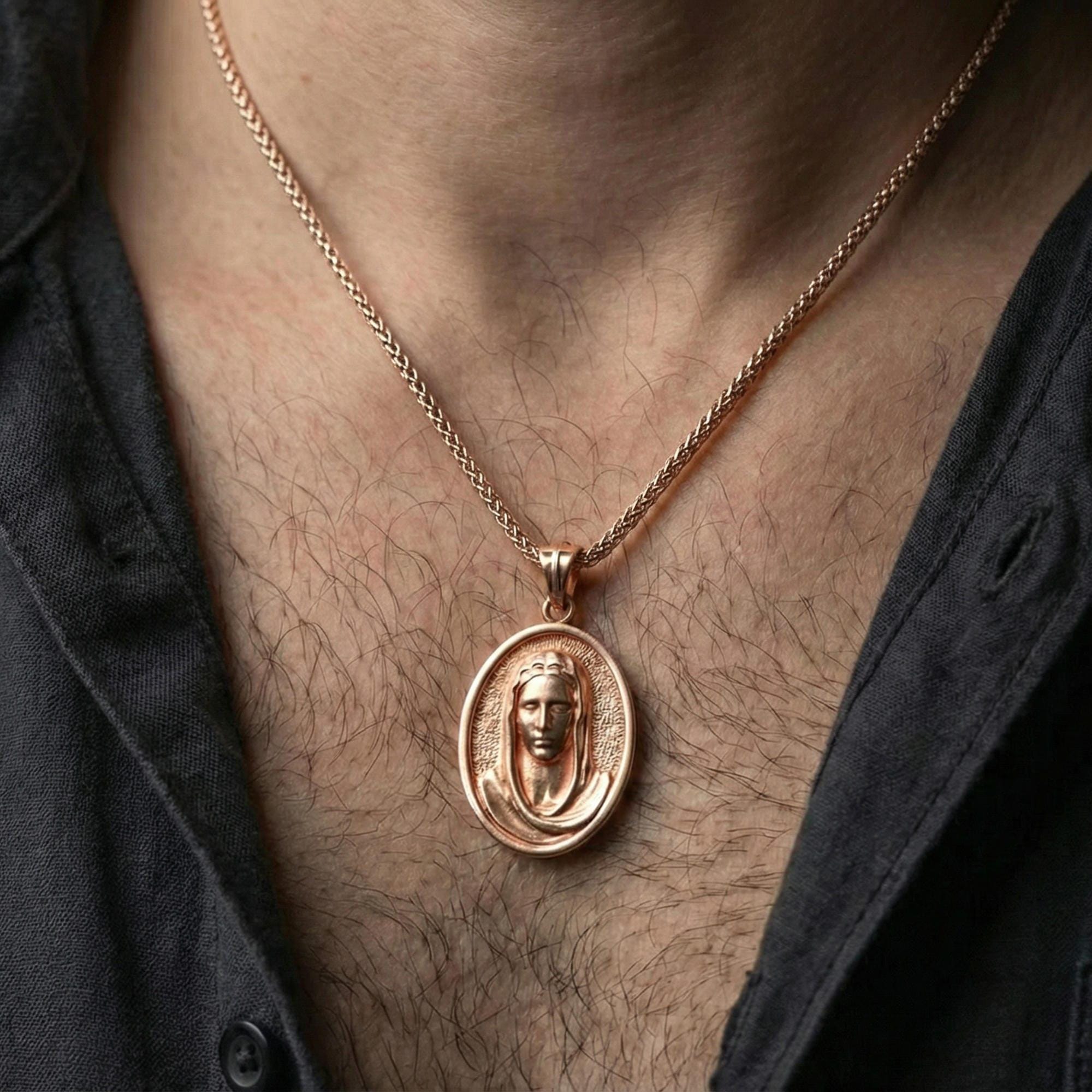 Rose gold plated Veiled Madonna pendant necklace worn on neck, lifestyle composition with dark clothing, crisp oval medallion silhouette