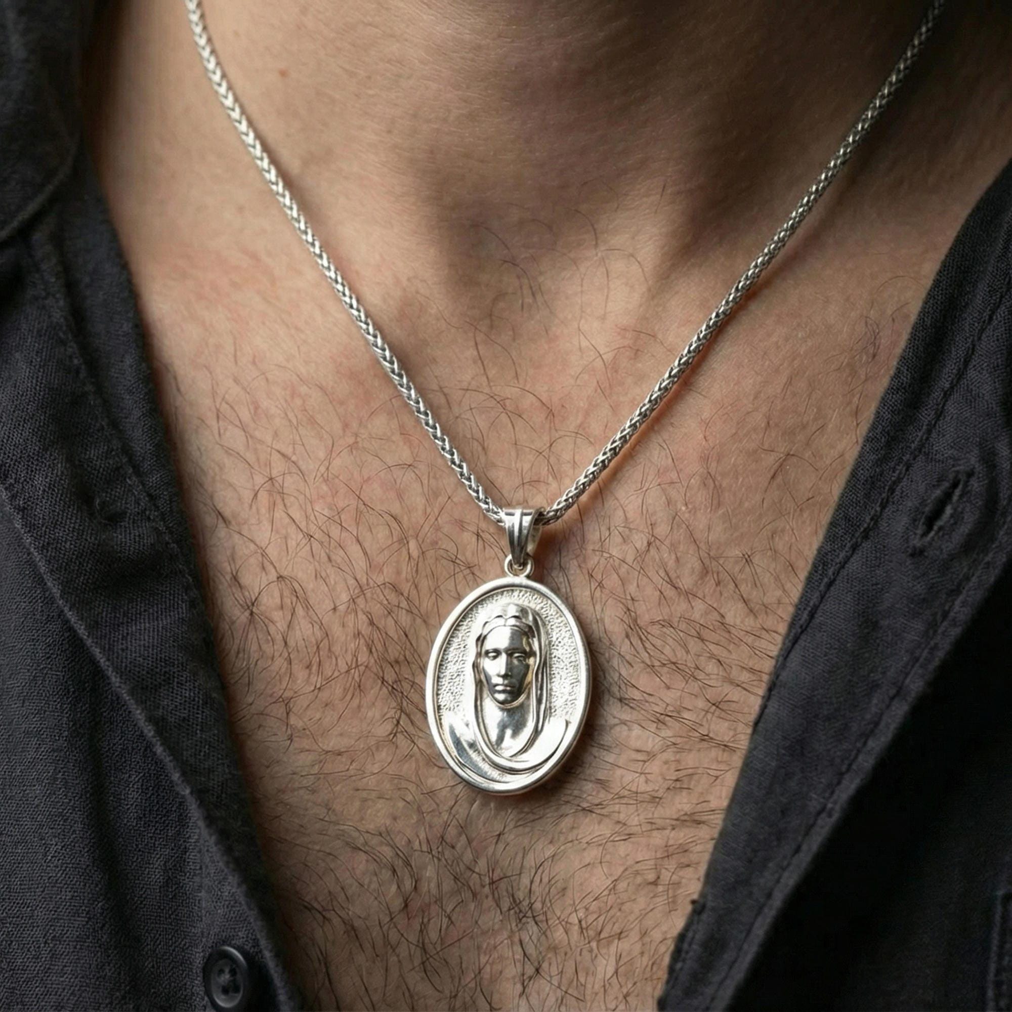 Polished silver Veiled Madonna pendant on chain worn on neck, natural lifestyle framing, Virgin Mary relief clearly visible