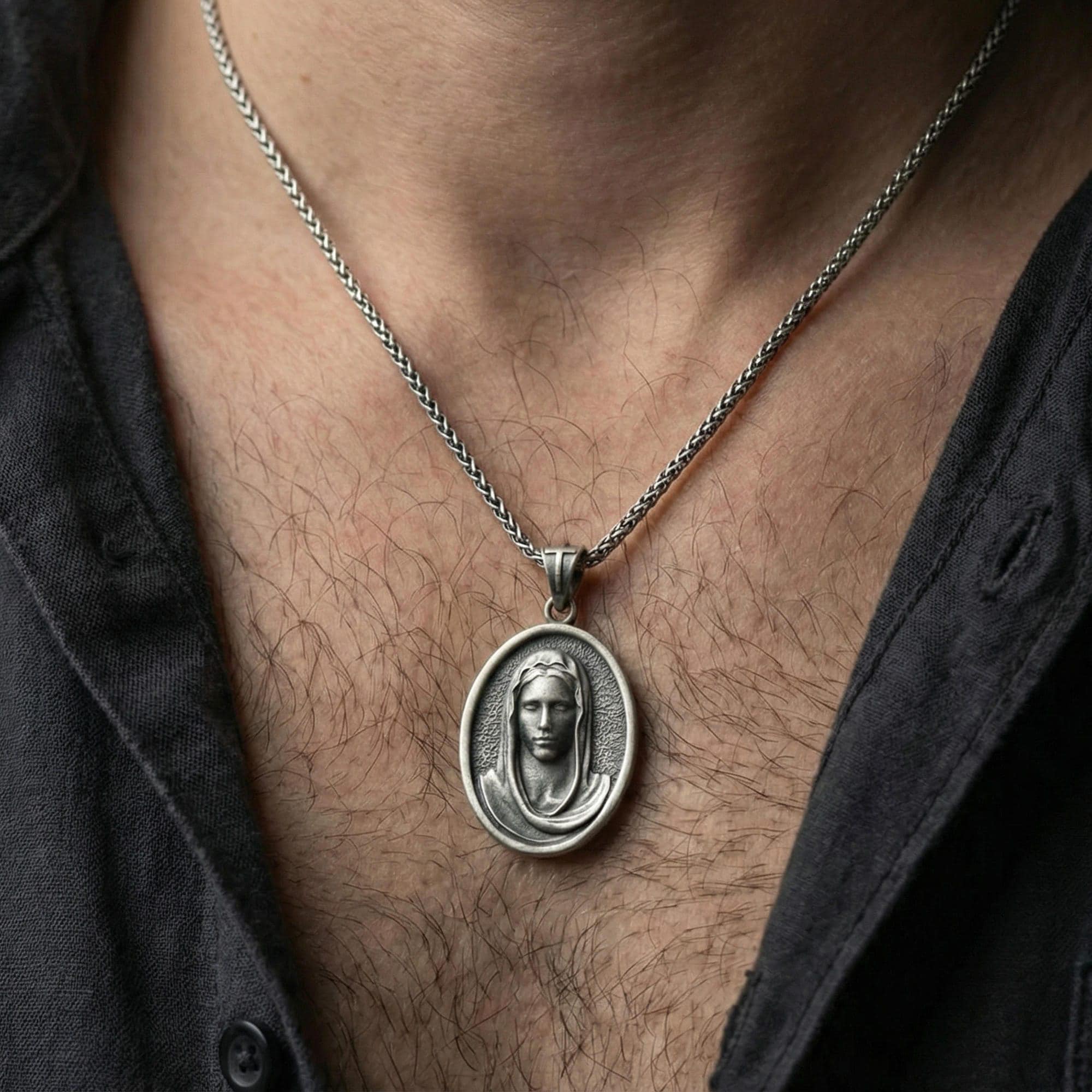 Oxidized Veiled Madonna pendant necklace worn on neck, lifestyle close-up on dark outfit, oval medallion centered