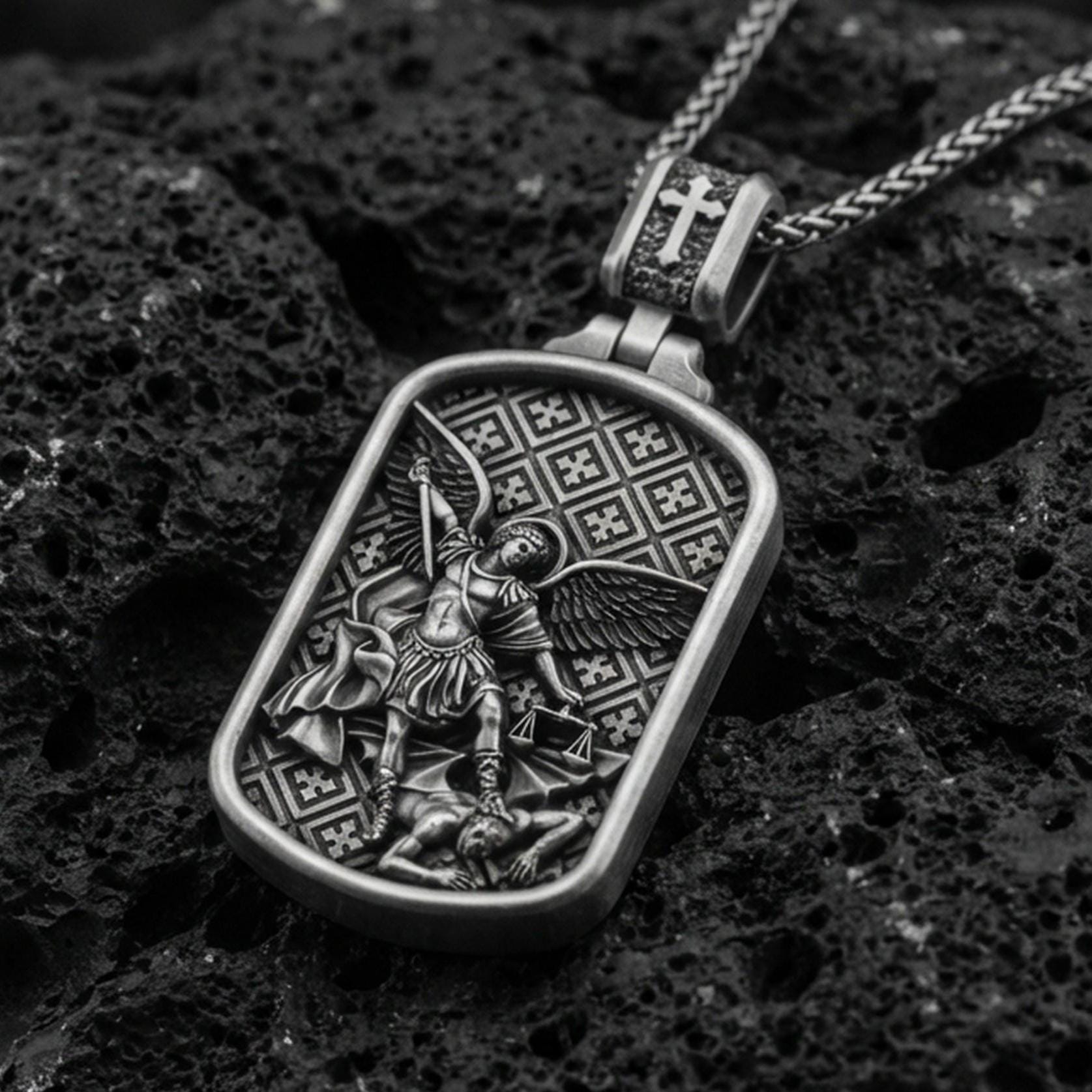 Oxidized Archangel Michael dog tag pendant on textured volcanic rock, macro close-up, angel defeating demon relief, premium studio lighting