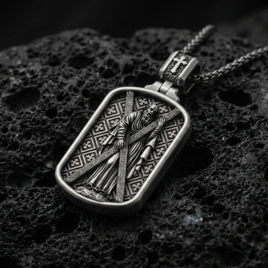 Oxidized Saint Andrew dog tag pendant on volcanic rock, macro close-up, apostle holding cross relief, premium studio lighting