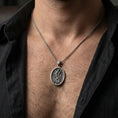 Load image into Gallery viewer, Oxidized Saint Andrew oval pendant necklace worn on neck, dark outfit lifestyle close-up, pendant centered and clear
