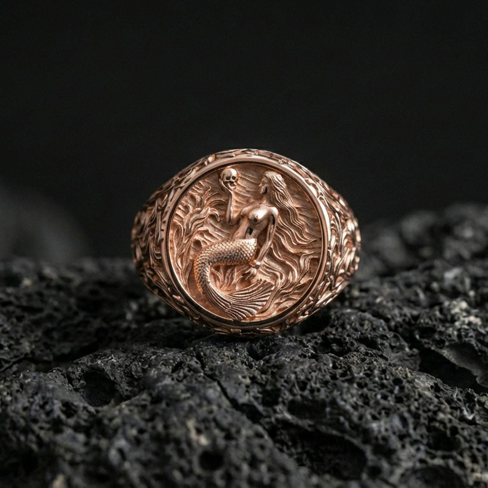 Rose gold plated mermaid ring on volcanic rock surface, mermaid motif with coastal waves and fine scrollwork, high-end studio lighting