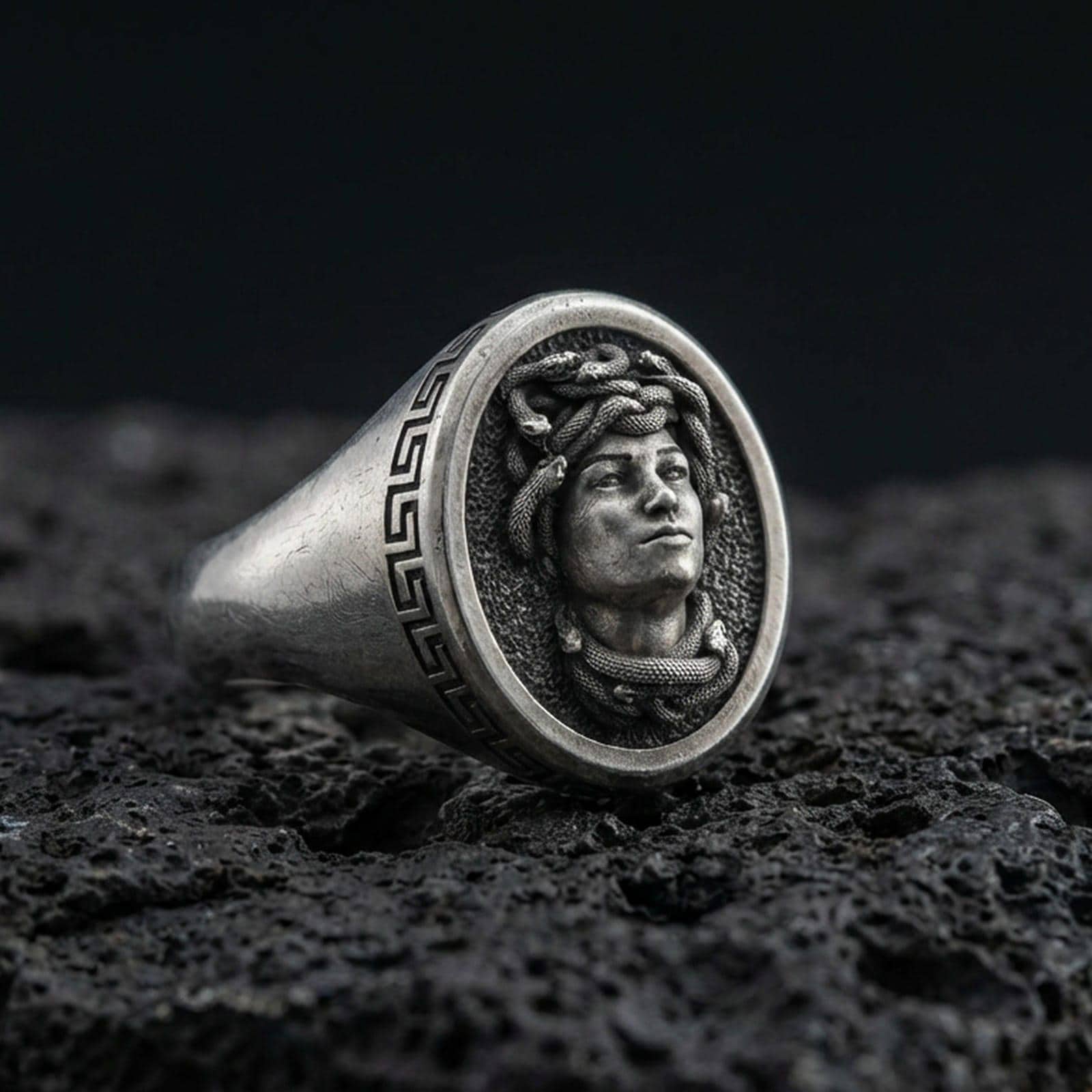 Oxidized sterling silver Medusa signet ring with Greek key border on volcanic rock background