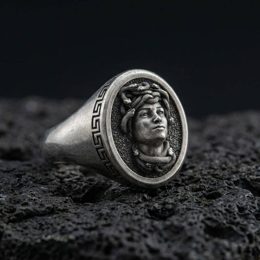 Oxidized sterling silver Medusa signet ring with Greek key border on volcanic rock background