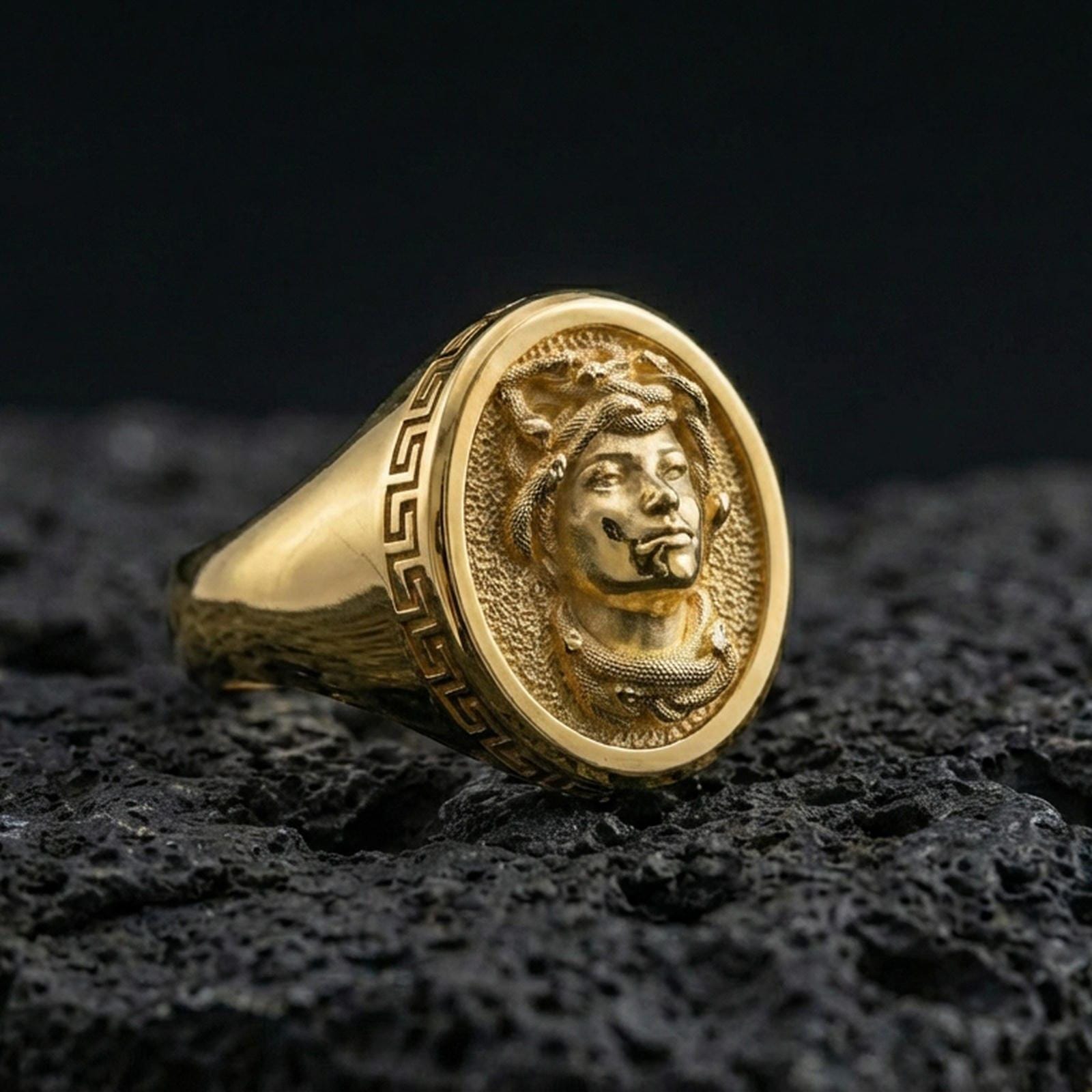 Gold plated Medusa signet ring with ancient Greek border detail photographed on volcanic rock surface
