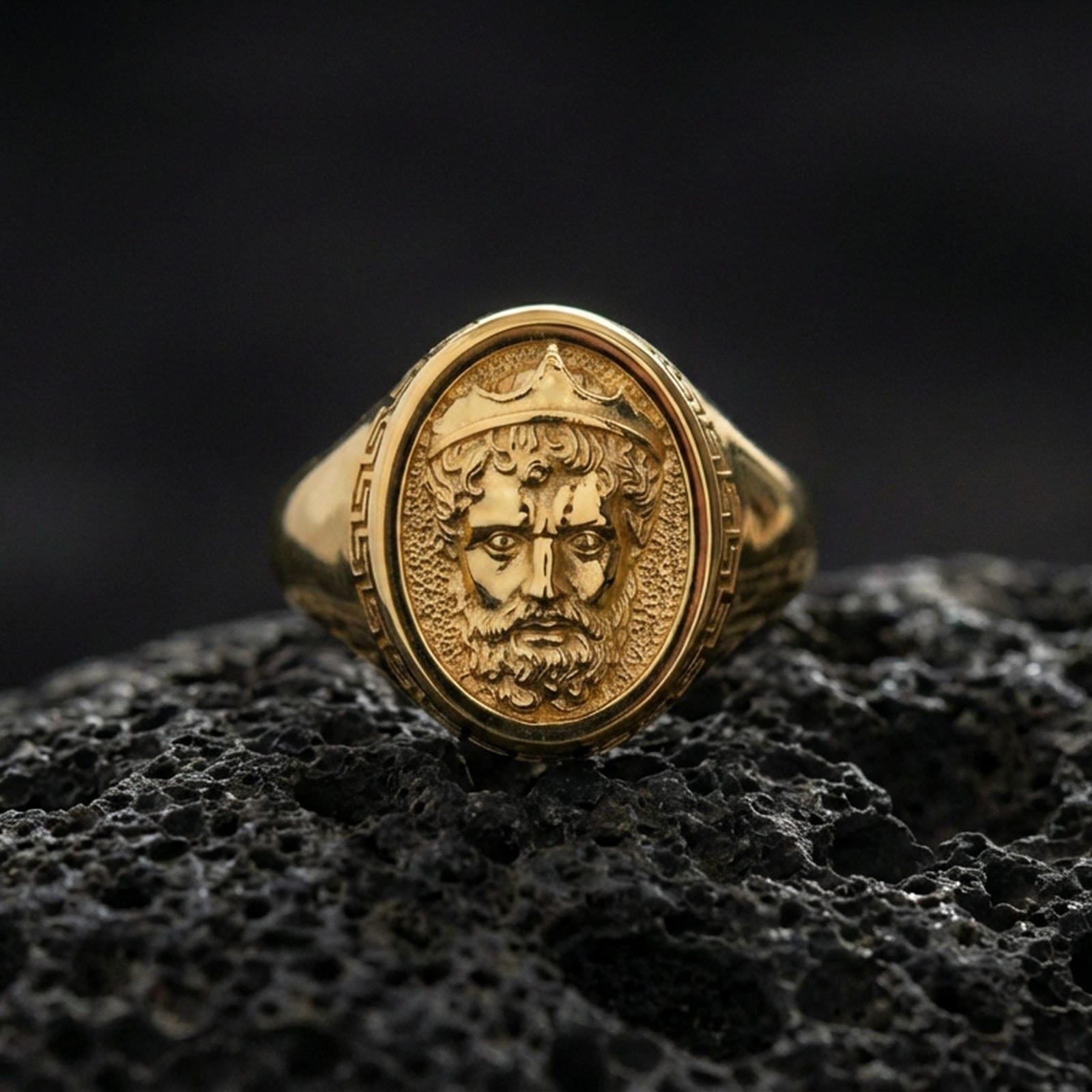 Gold plated Poseidon ring displayed on porous volcanic rock, Greek mythology king portrait, bold signet style, premium macro shot