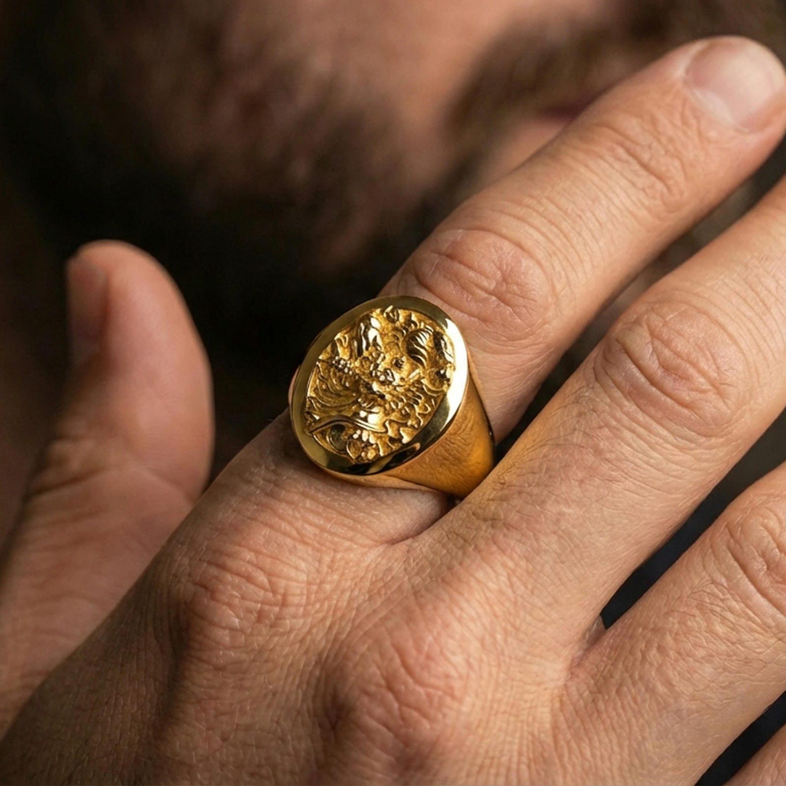 Gold plated signet ring worn on finger, bold carved demon motif, masculine lifestyle close-up