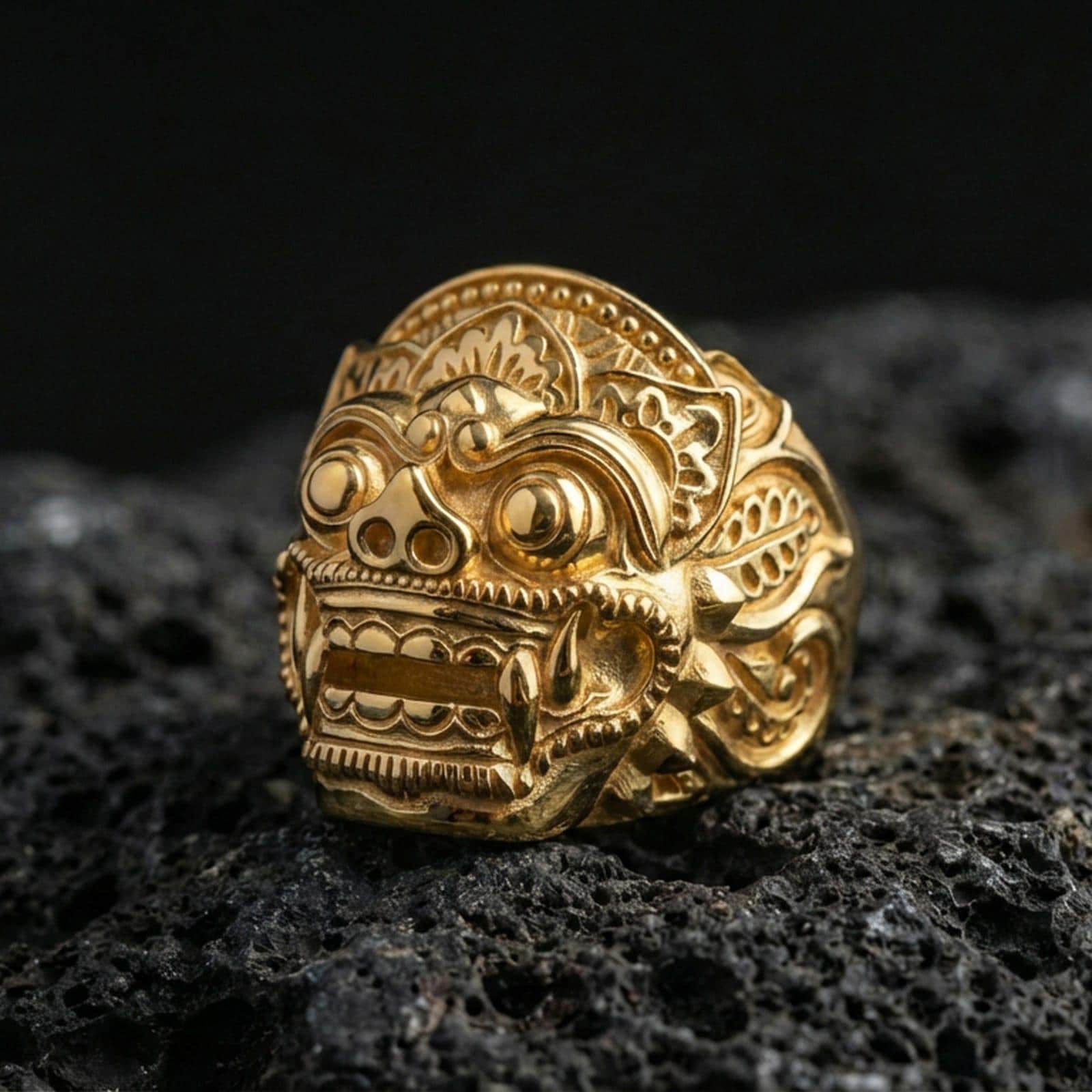 Balinese Barong god gold plated ring on volcanic rock, bold gothic guardian face design, premium macro shot