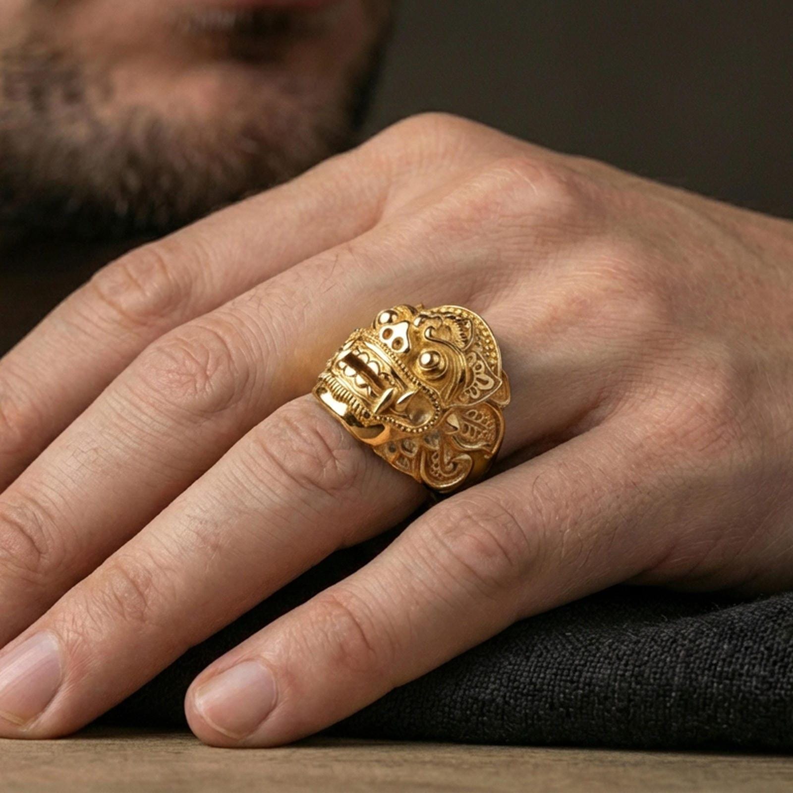 Balinese Barong god gold plated ring worn on finger, dramatic demon mask face design, masculine lifestyle close-up