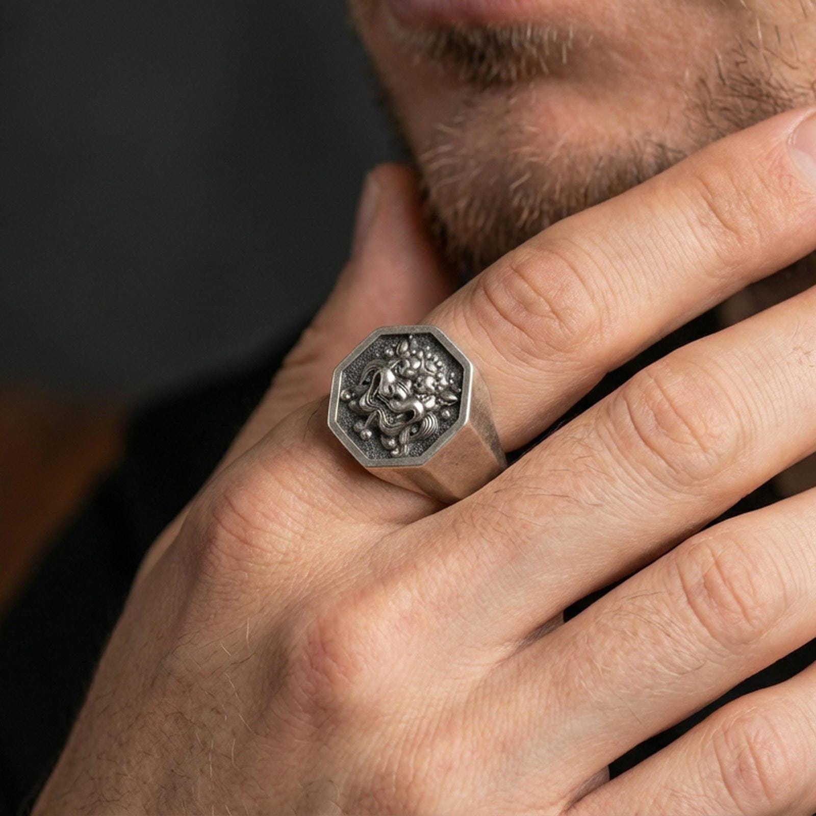 Octagon sterling silver oxidized Foo Dog signet ring worn on finger, Chinese guardian lion relief visible, lifestyle hand close-up