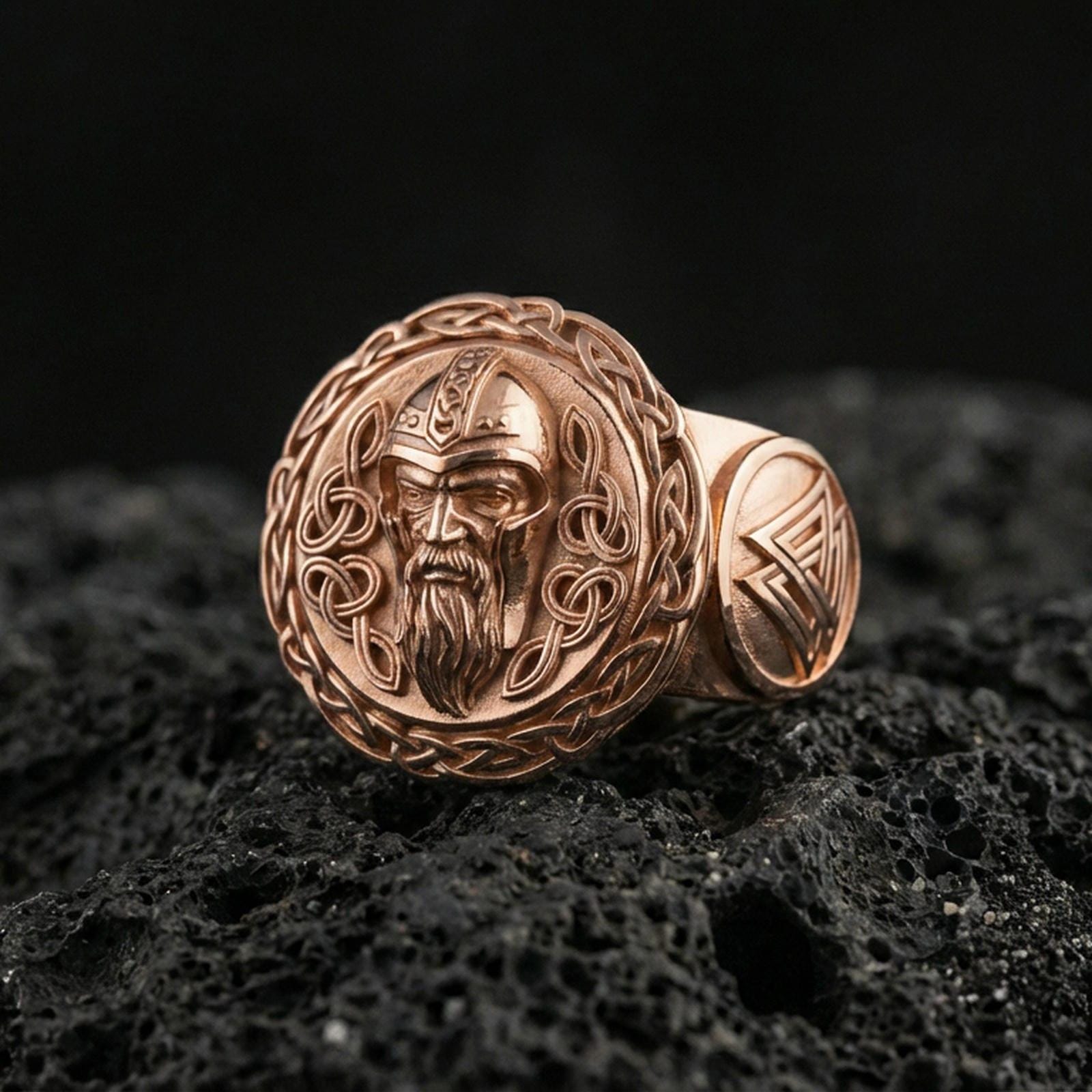 Odin the All-Father ring in a rose gold plated finish on volcanic rock, Norse pagan signet with Celtic knot frame, luxury studio close-up