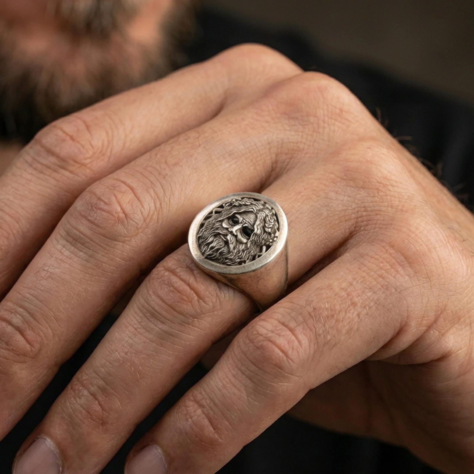 Oval Odin Norse god signet ring in an oxidized finish worn on finger, bearded portrait detail visible, lifestyle hand close-up
