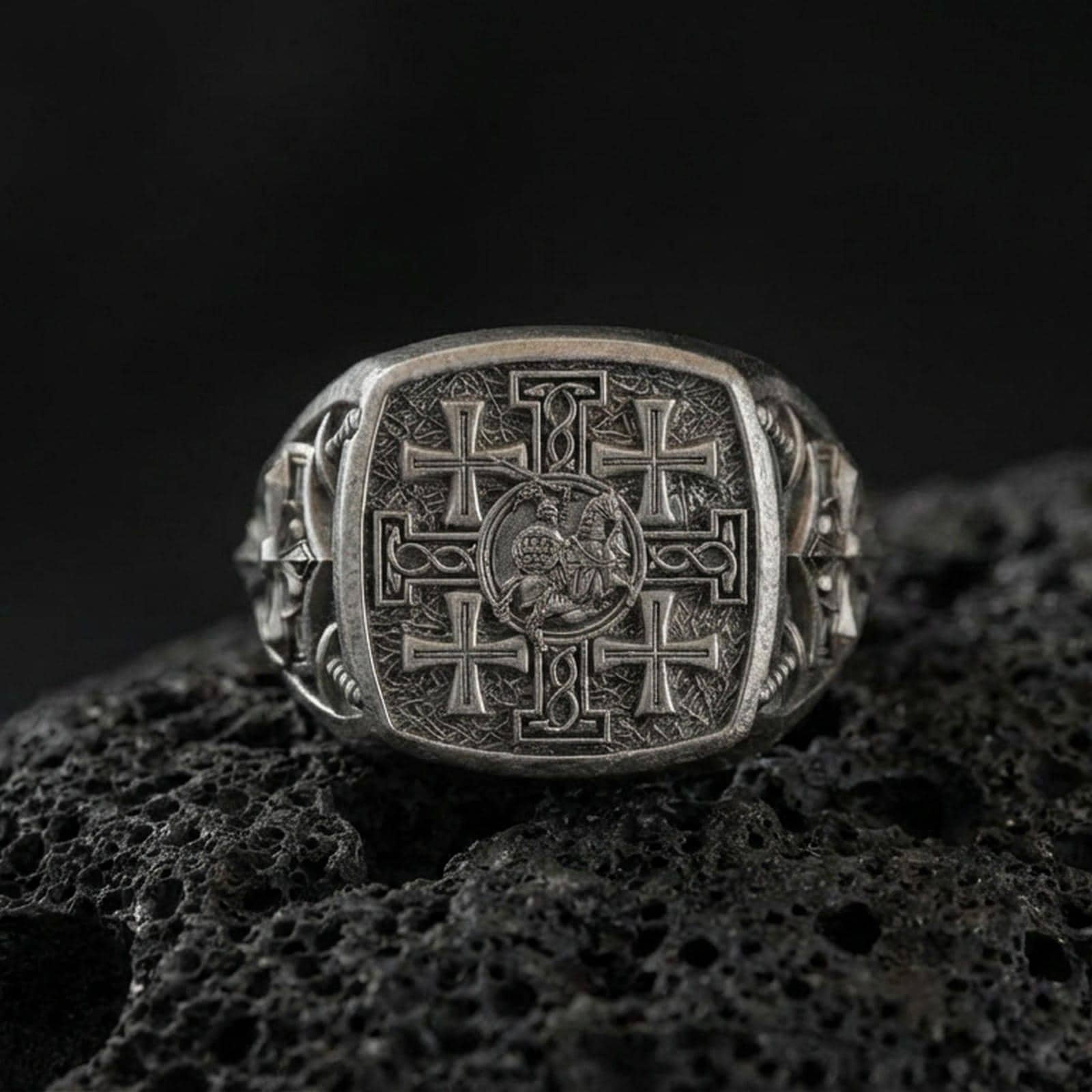 Jerusalem Cross sterling silver signet ring in an oxidized finish on volcanic rock, medieval crusader cross engraving, macro studio product shot