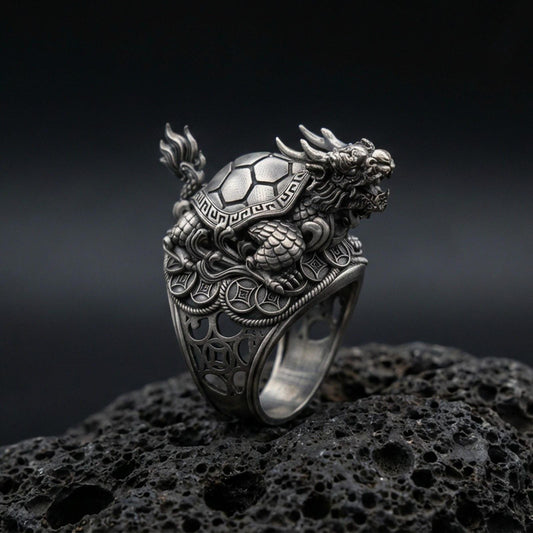 Sterling silver dragon turtle ring in an oxidized finish on volcanic rock, detailed Eastern mythical creature sculpture, macro studio product shot