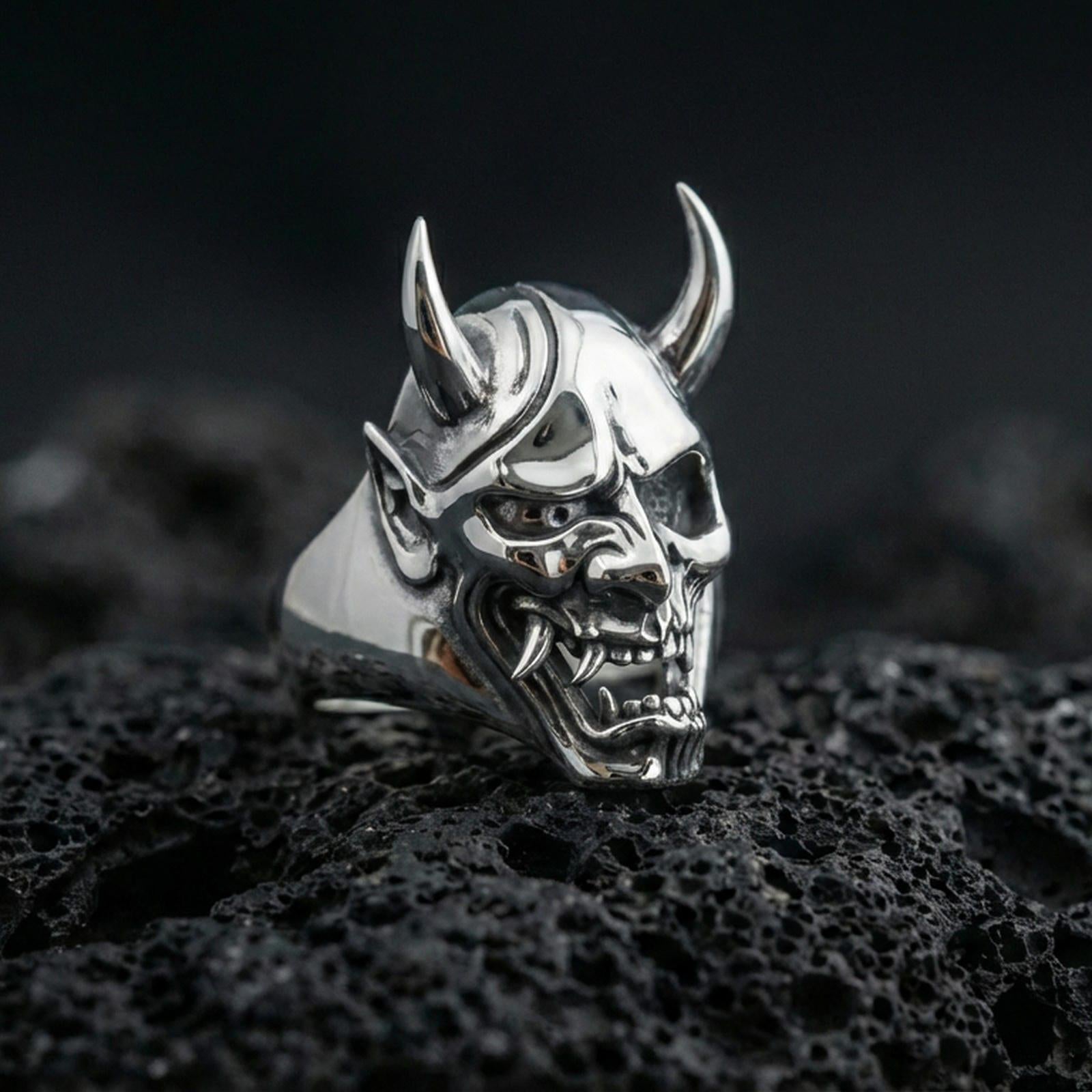 Undead oni mask ring in a gold plated finish on volcanic rock, Japanese demon skull design with sharp horn details, premium macro product image