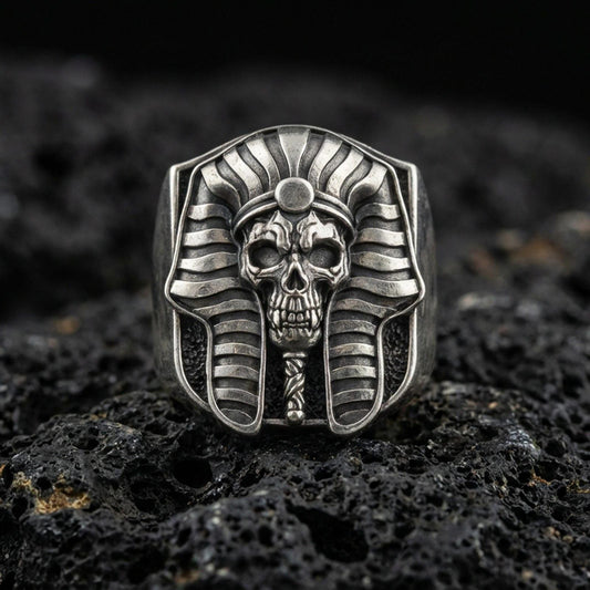 Sterling silver pharaoh skull ring in an oxidized finish on volcanic rock, ancient Egypt mummy mask design, macro studio product shot