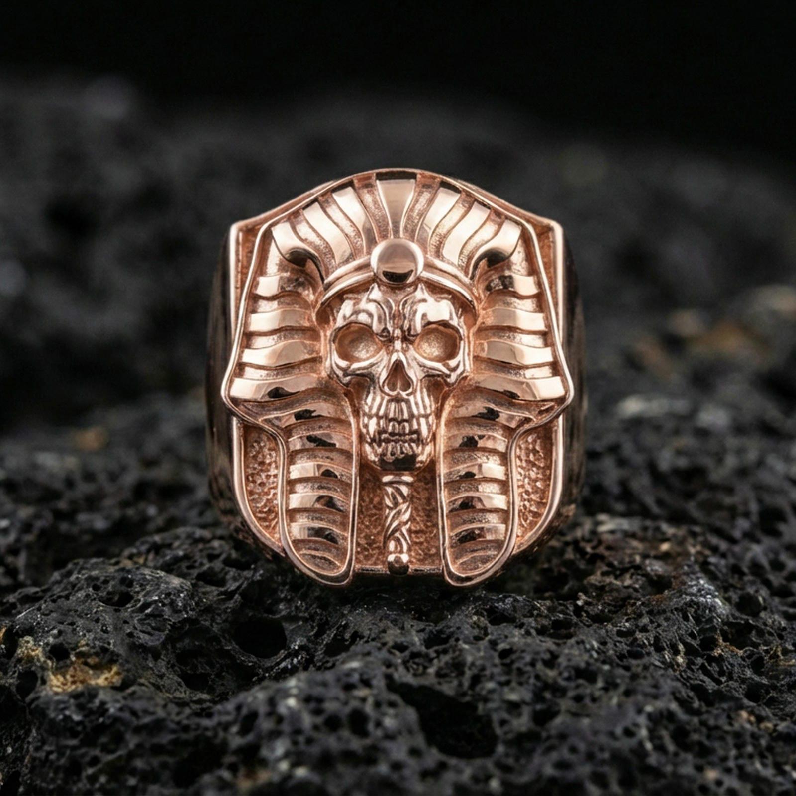 Pharaoh skull ring in a rose gold plated finish on volcanic rock, ornate Egyptian headdress with skull face detail, luxury studio close-up