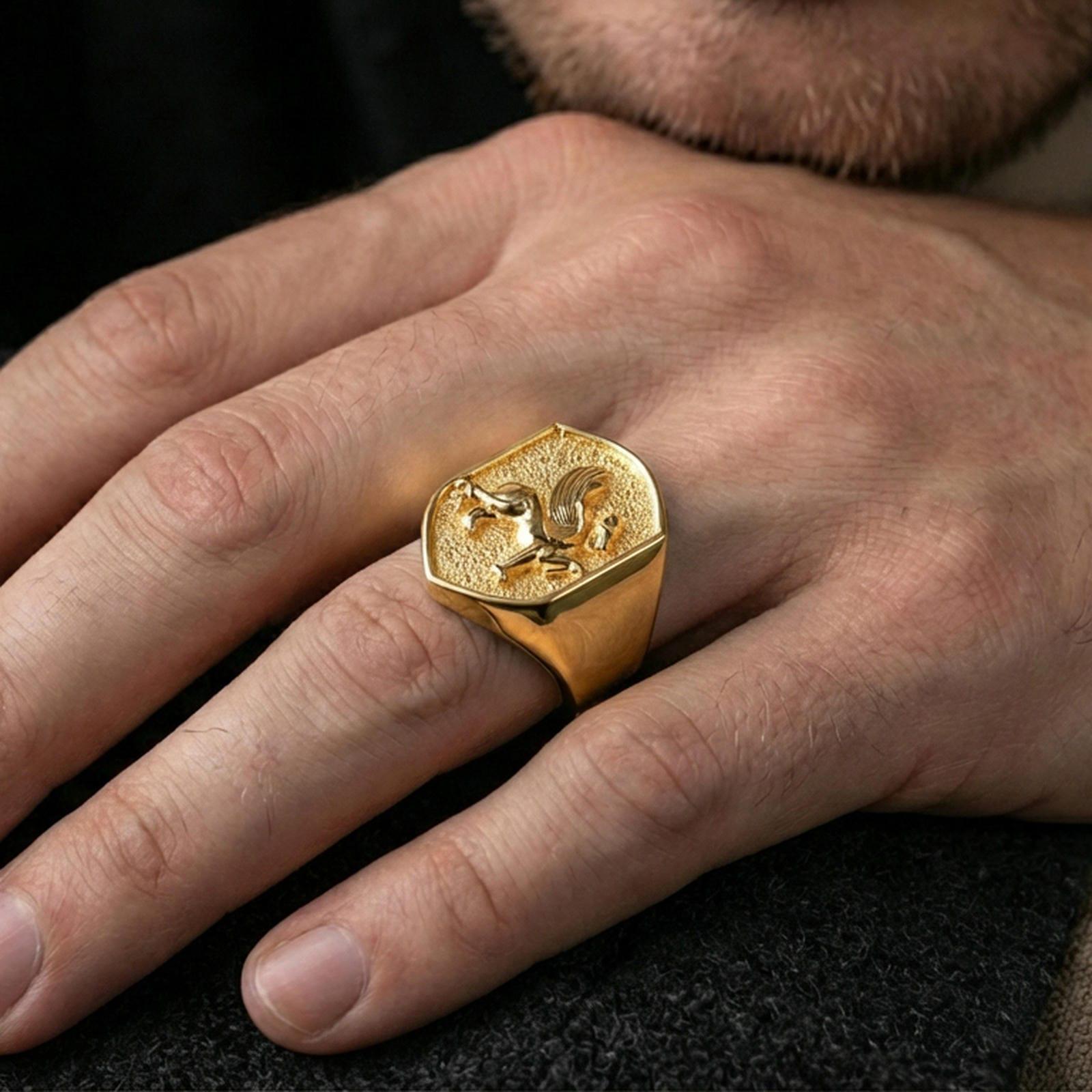 Gryphon signet ring in a gold plated finish worn on finger, bold mythical griffin statement design, masculine lifestyle close-up