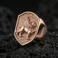 Load image into Gallery viewer, Griffin shield signet ring in a rose gold plated finish on volcanic rock, ornate winged gryphon relief detail, luxury studio close-up
