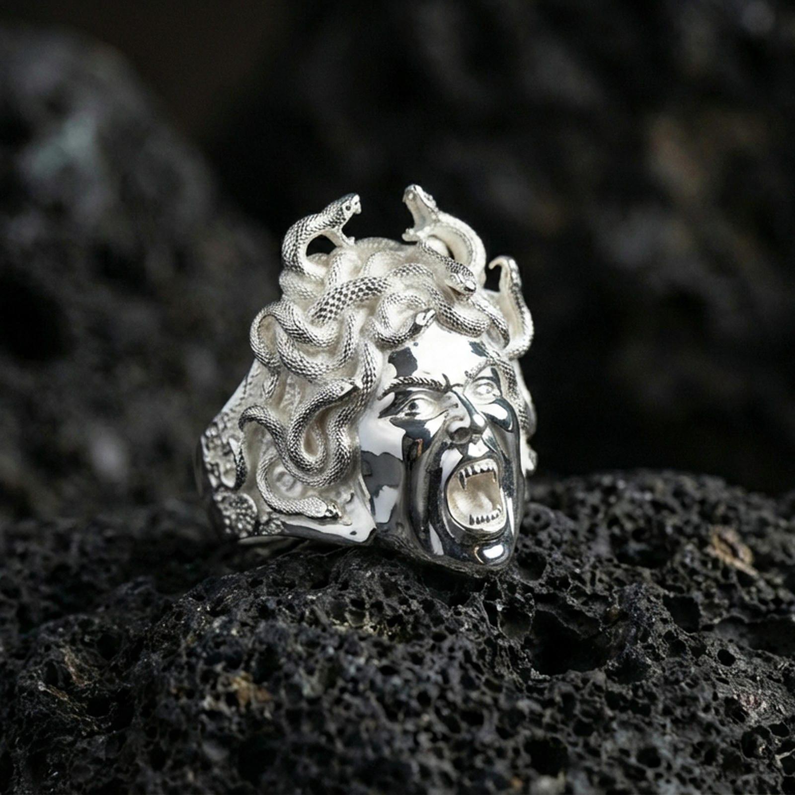 Sterling silver Medusa ring in polished silver finish on volcanic rock, detailed gorgon face with coiled snake hair, close-up product photo