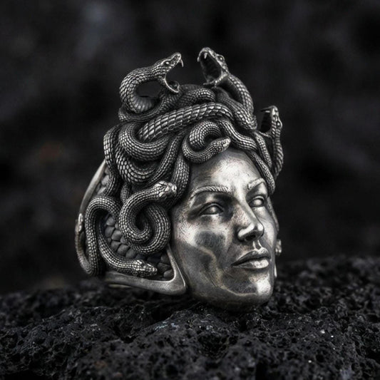 Sterling silver Medusa ring in an oxidized finish on volcanic rock, gorgon goddess portrait with detailed snake hair texture, macro studio product shot