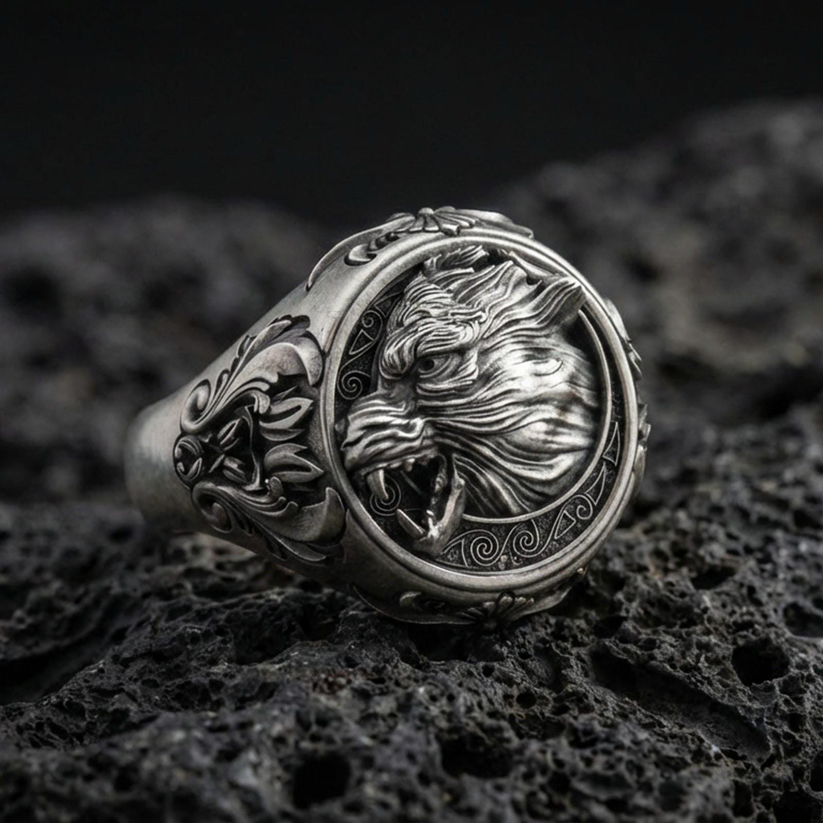 Sterling silver Fenrir wolf signet ring in an oxidized finish on volcanic rock, snarling wolf head relief with Celtic knot side engravings, macro studio product shot