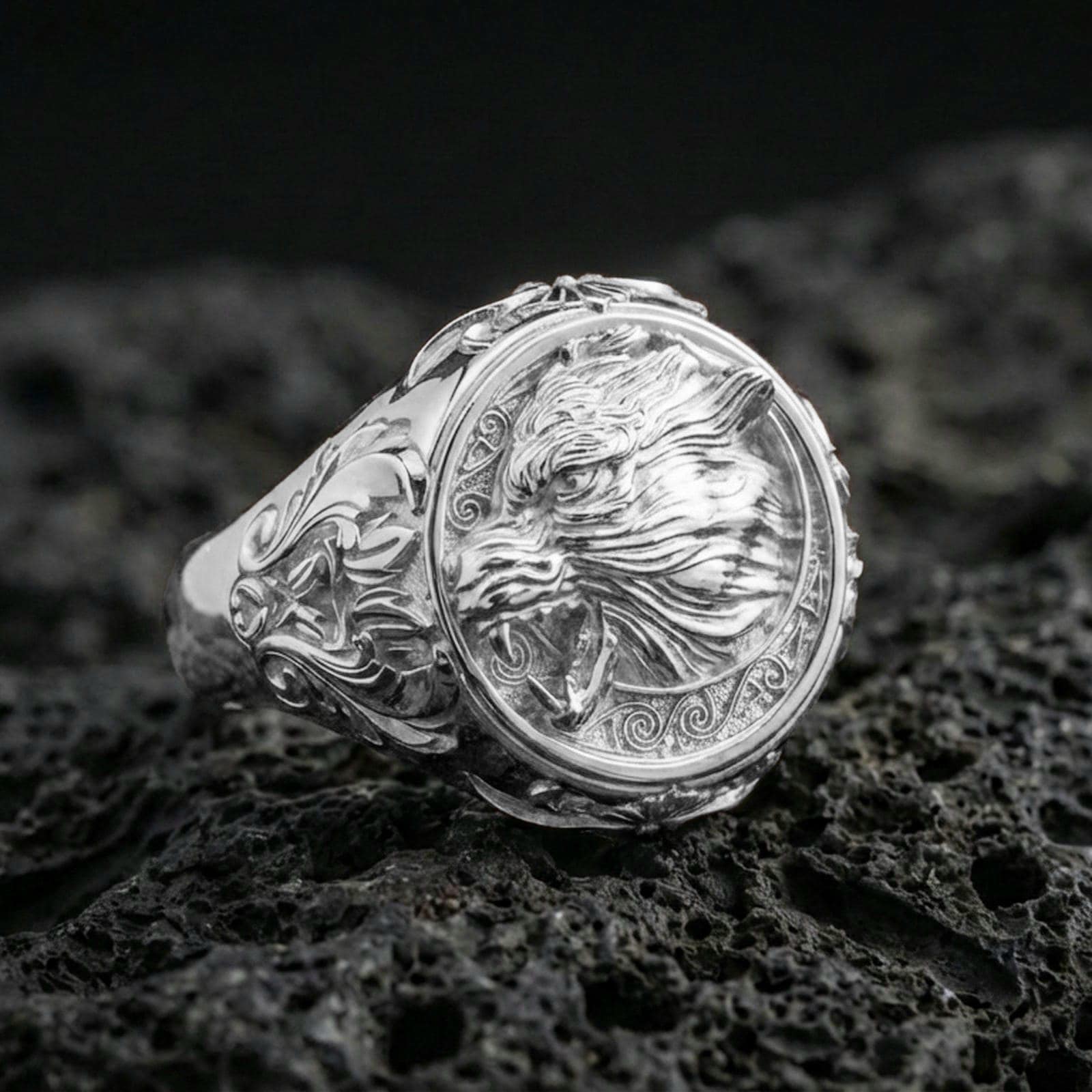 Fenrir wolf ring in polished silver finish on volcanic rock, detailed Norse wolf portrait with ornamental border and side scrollwork, close-up product photo