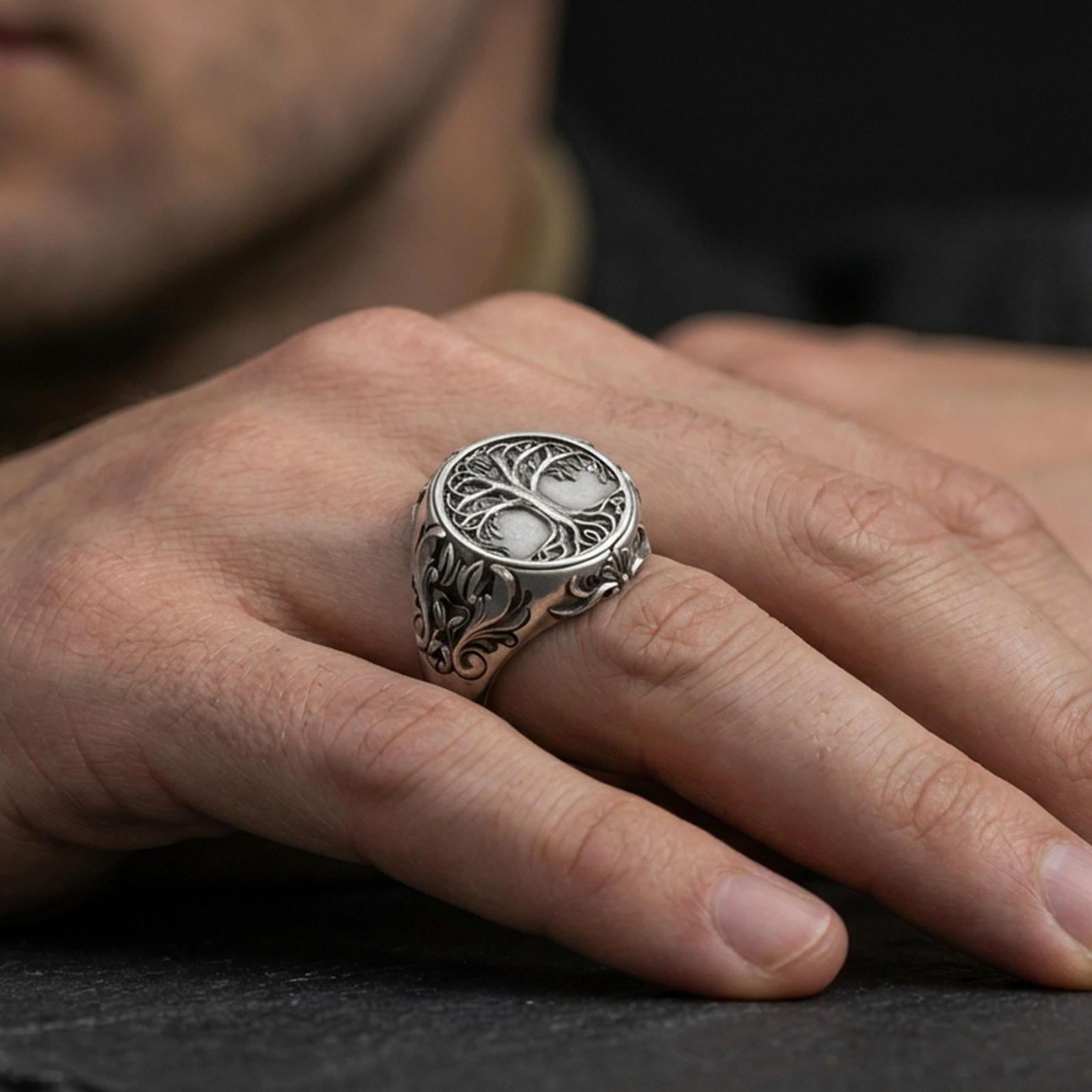 Sterling silver Yggdrasil ring in an oxidized finish worn on finger, tree of life emblem and side scrollwork visible, lifestyle hand close-up