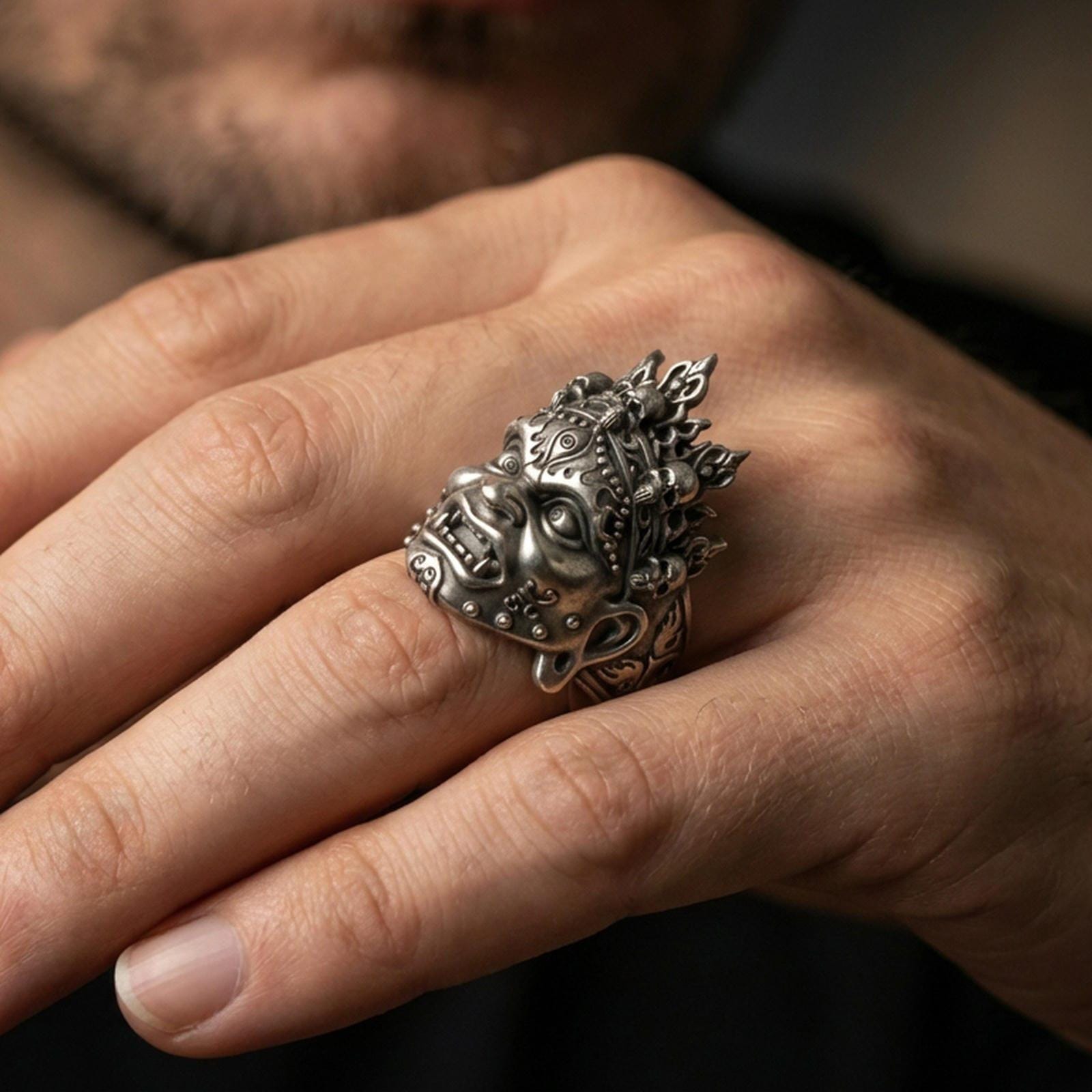 Sterling silver Yama mask ring in an oxidized finish worn on finger, skull crown and fierce expression visible, dark gothic lifestyle close-up