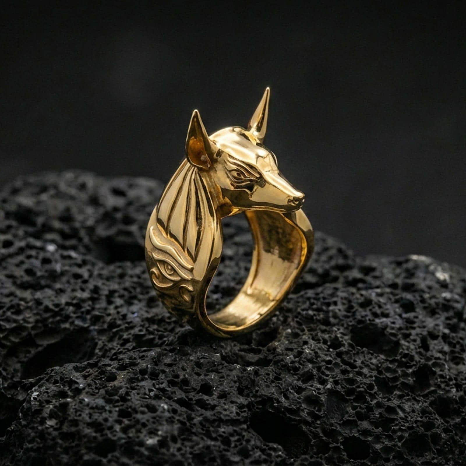 Egyptian Anubis ring in a gold plated finish on volcanic rock, Eye of Horus detail and sleek jackal head design, luxury macro jewelry image