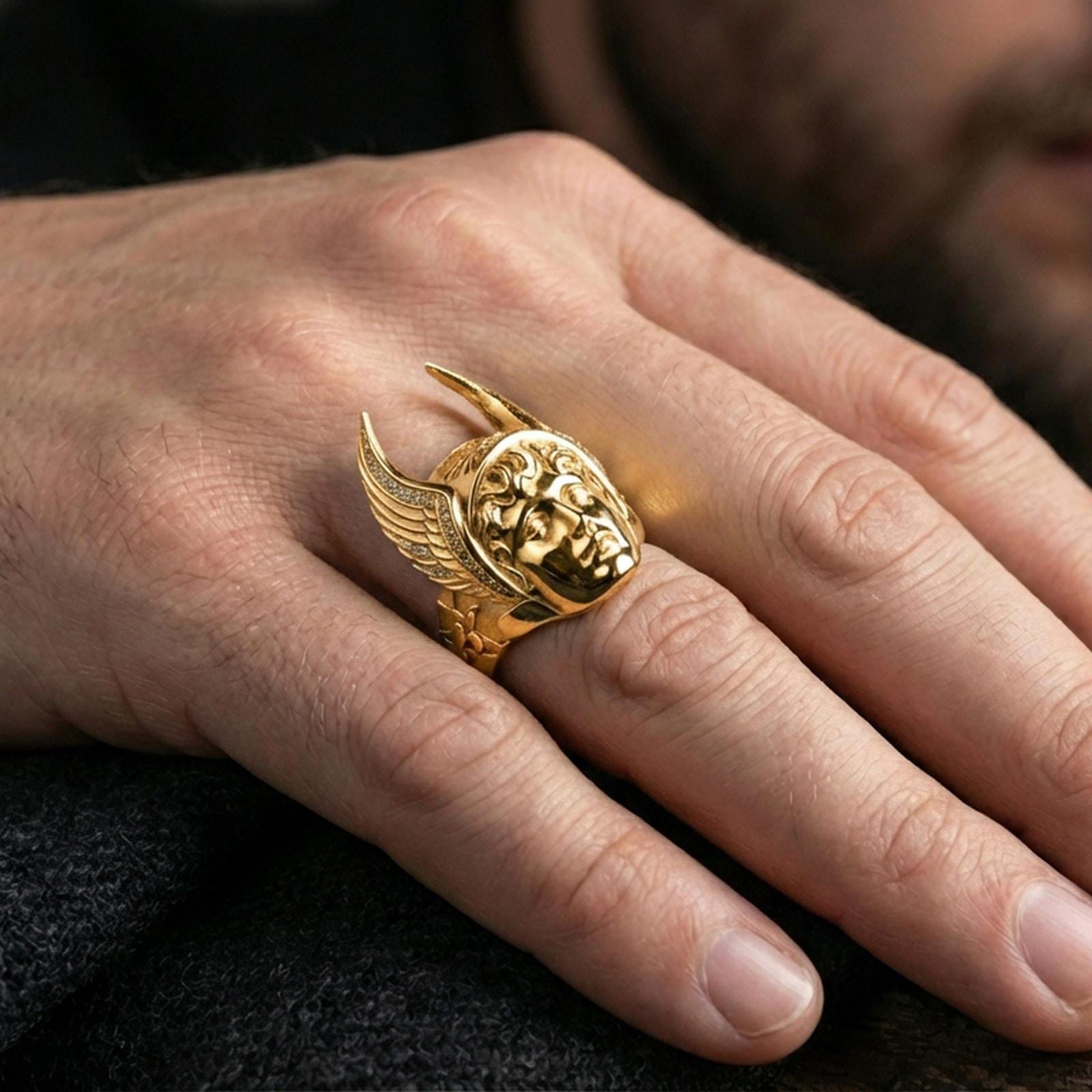 Hermes ring in a rose gold plated finish worn on finger, winged helmet feather texture and sculpted portrait, lifestyle close-up