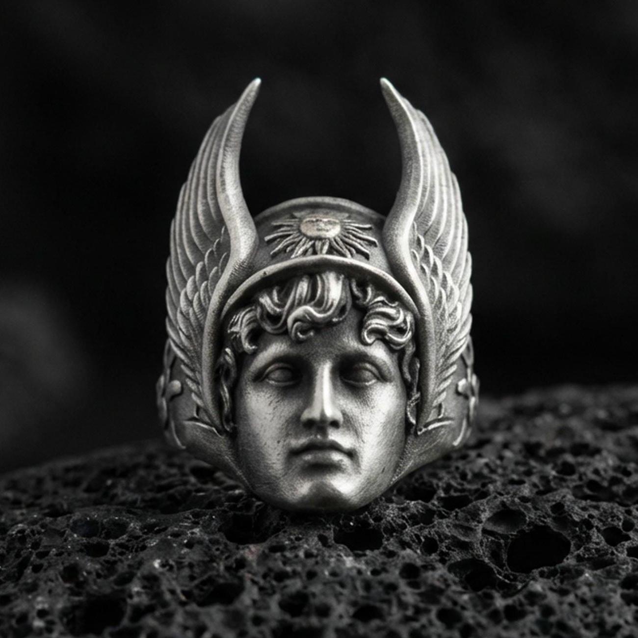 Sterling silver Hermes ring in an oxidized finish on volcanic rock, Greek god face with winged helmet relief, dramatic macro studio shot