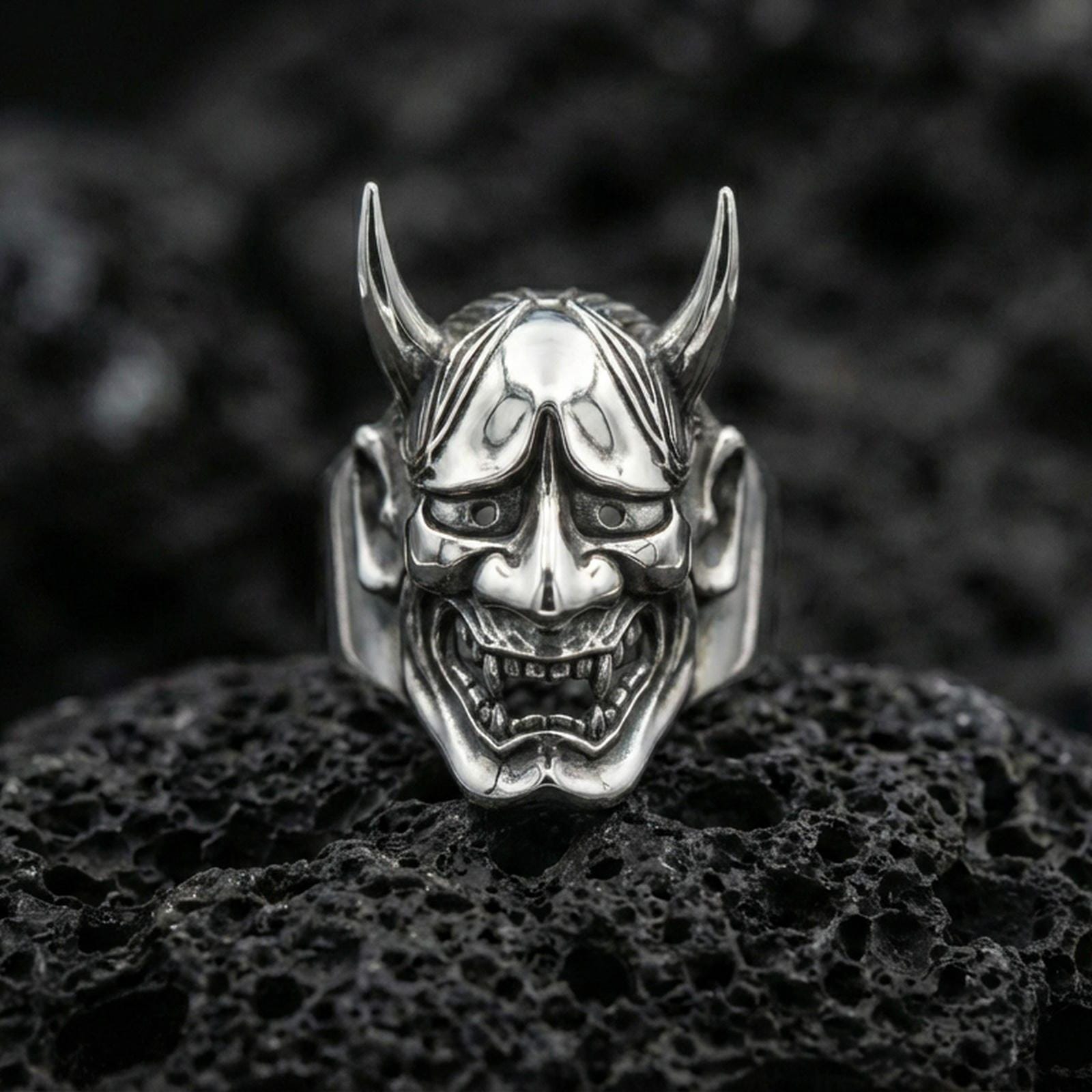 Hannya demon ring in polished silver finish on volcanic rock, sharp horn details and glossy highlights, premium close-up product photo