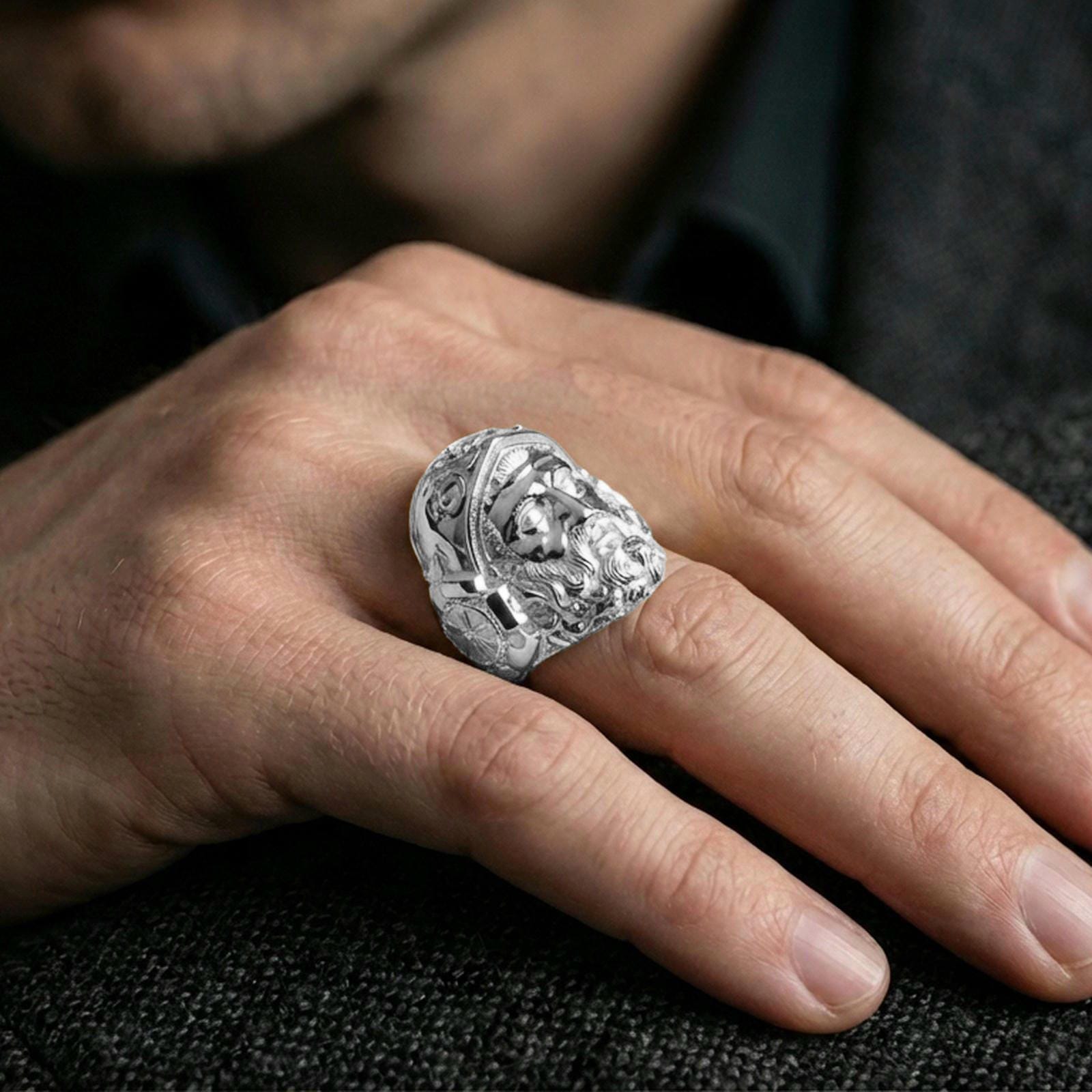 Polished silver Hephaestus ring on hand, minimalist-strong signet profile with high-relief Greek god of fire design