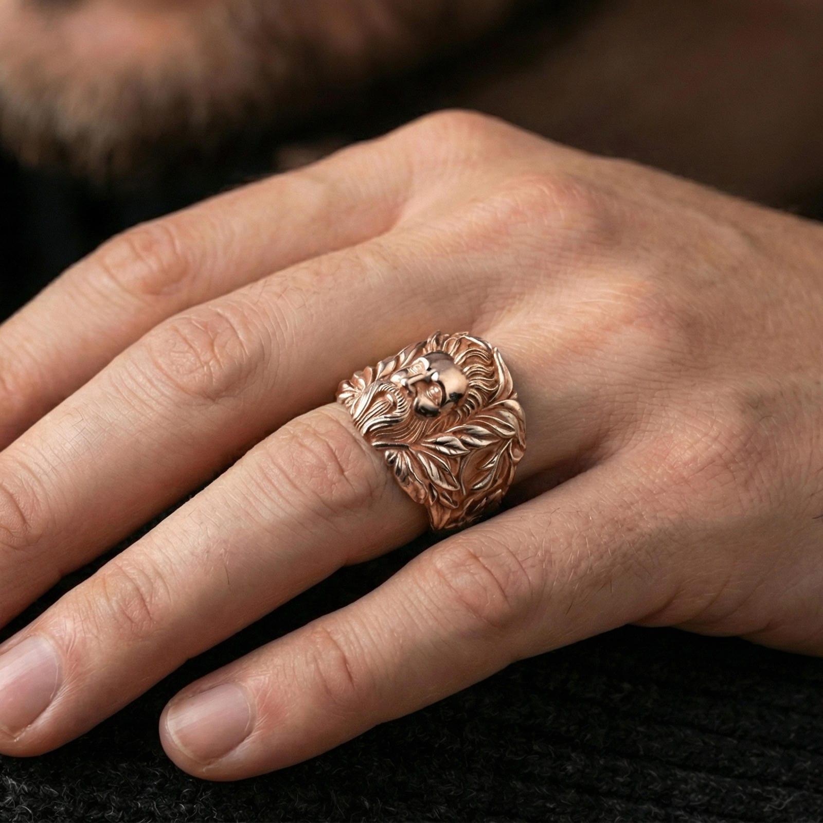Rose gold plated ring on finger, ornate face relief framed by laurel leaves, refined lifestyle hand shot for everyday wear