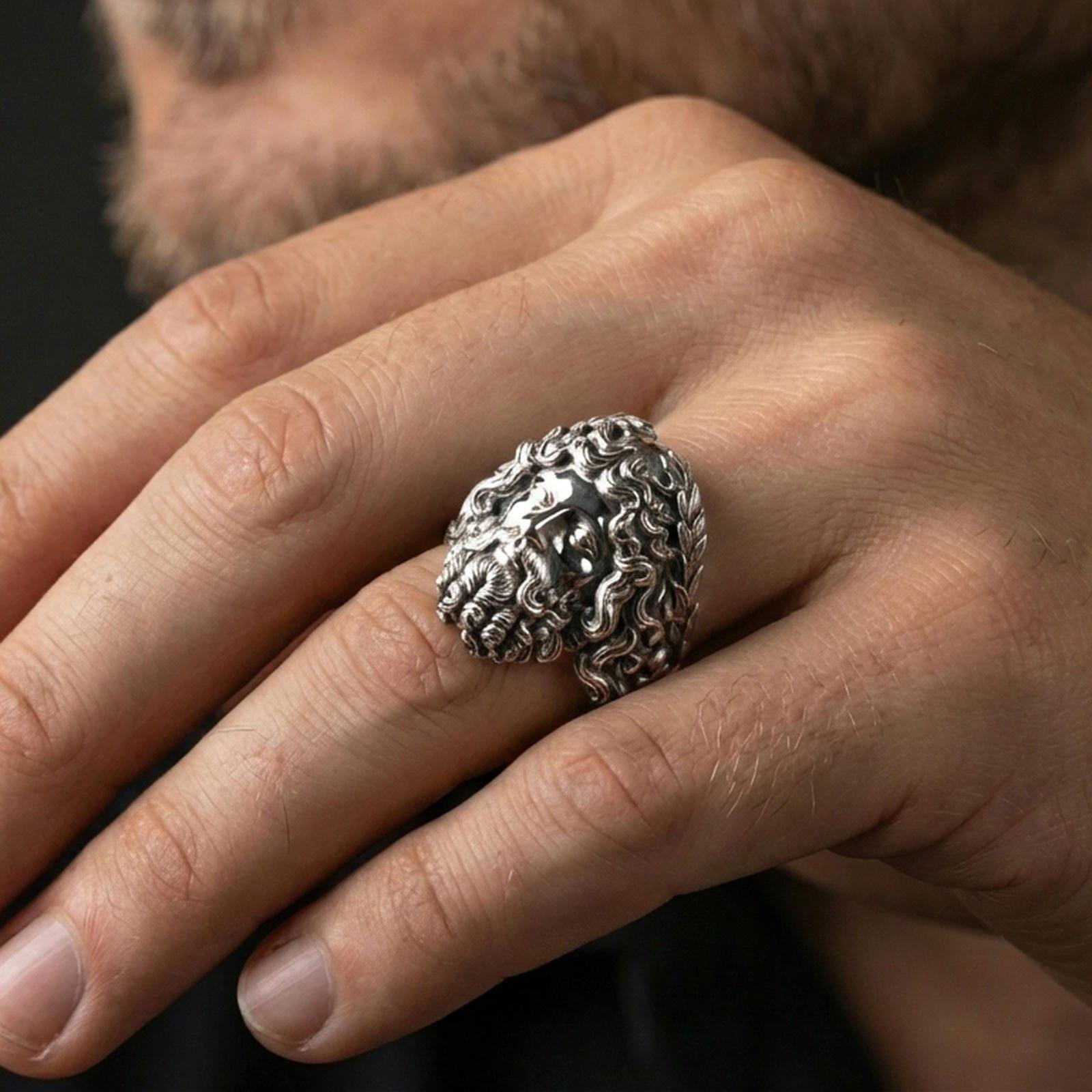 Polished silver Zeus ring on finger showcasing sculpted hair and beard details, clean lifestyle wear photo with natural lighting